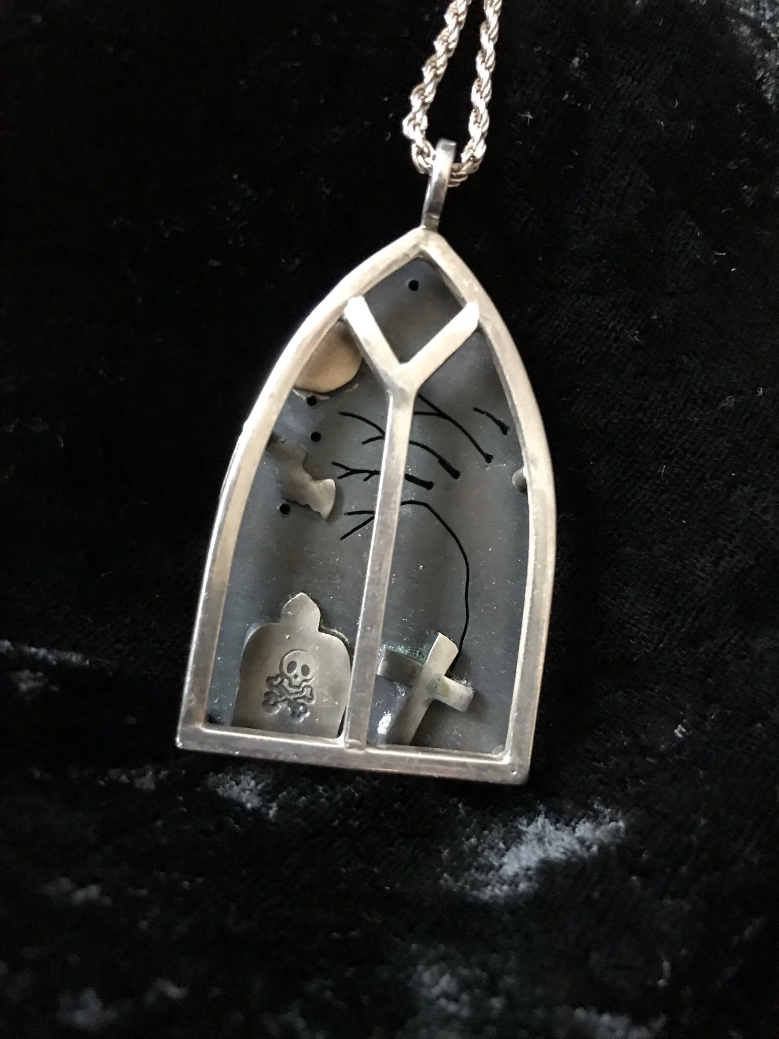 Gothic inspired Silver necklace with a pendant shaped like a church window featuring a skull, a cross. 