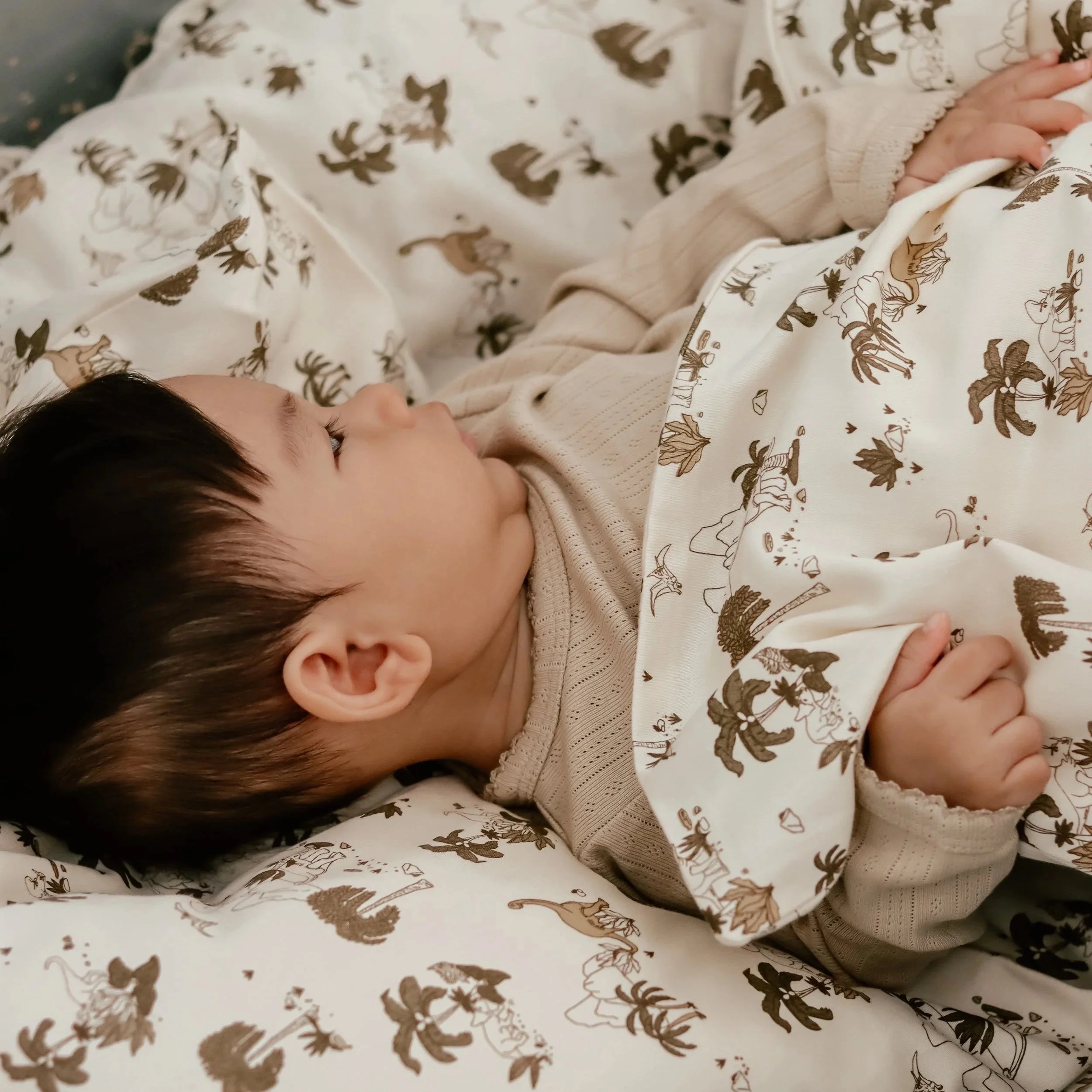 Baby bedding with dinosaur print, small illustrative drawings, handmade textile print