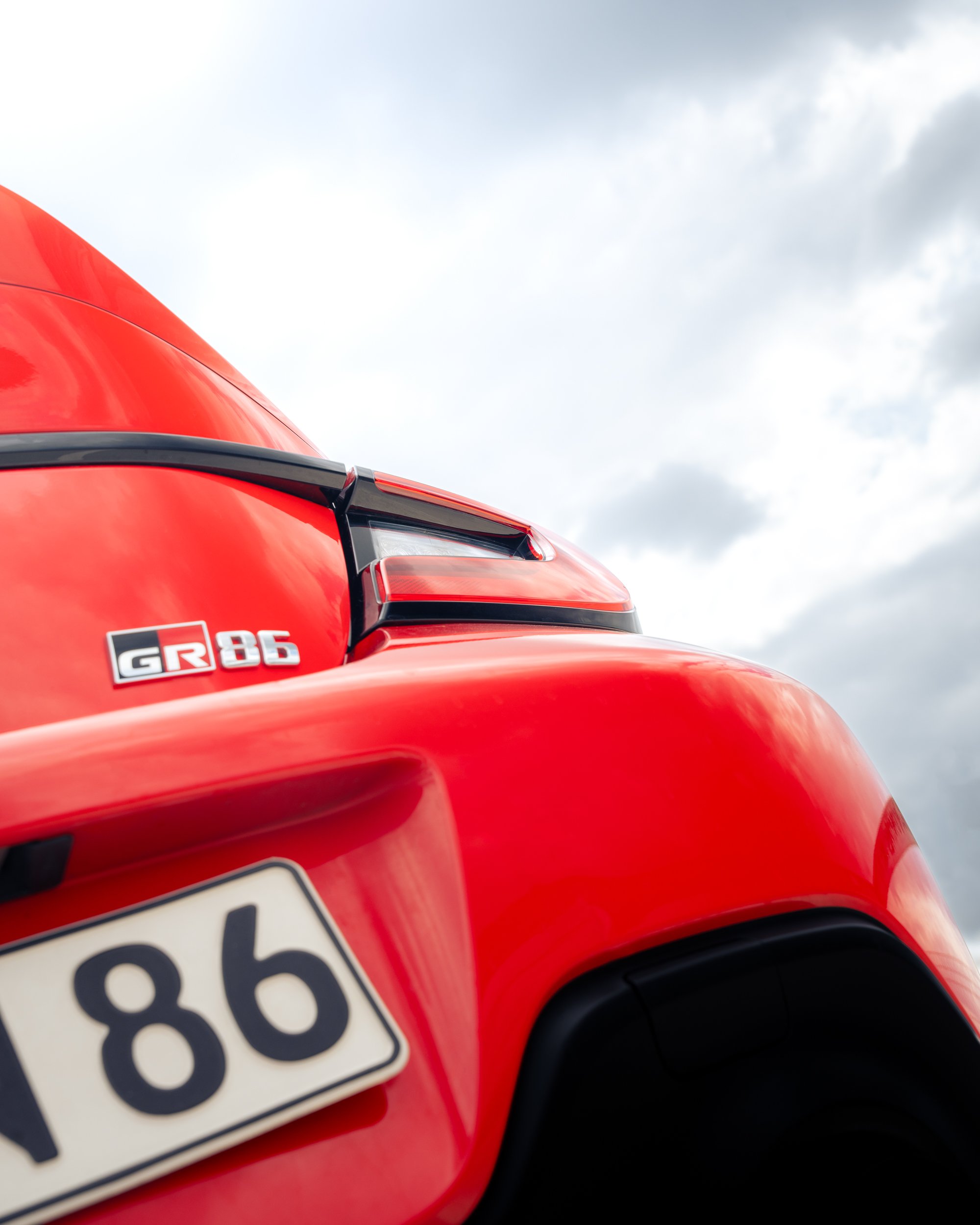Nahaufnahme des hinteren Teils eines roten Autos mit einem "GR 86" Emblem und einem deutschen Nummernschild, Blick nach oben gegen den Himmel.