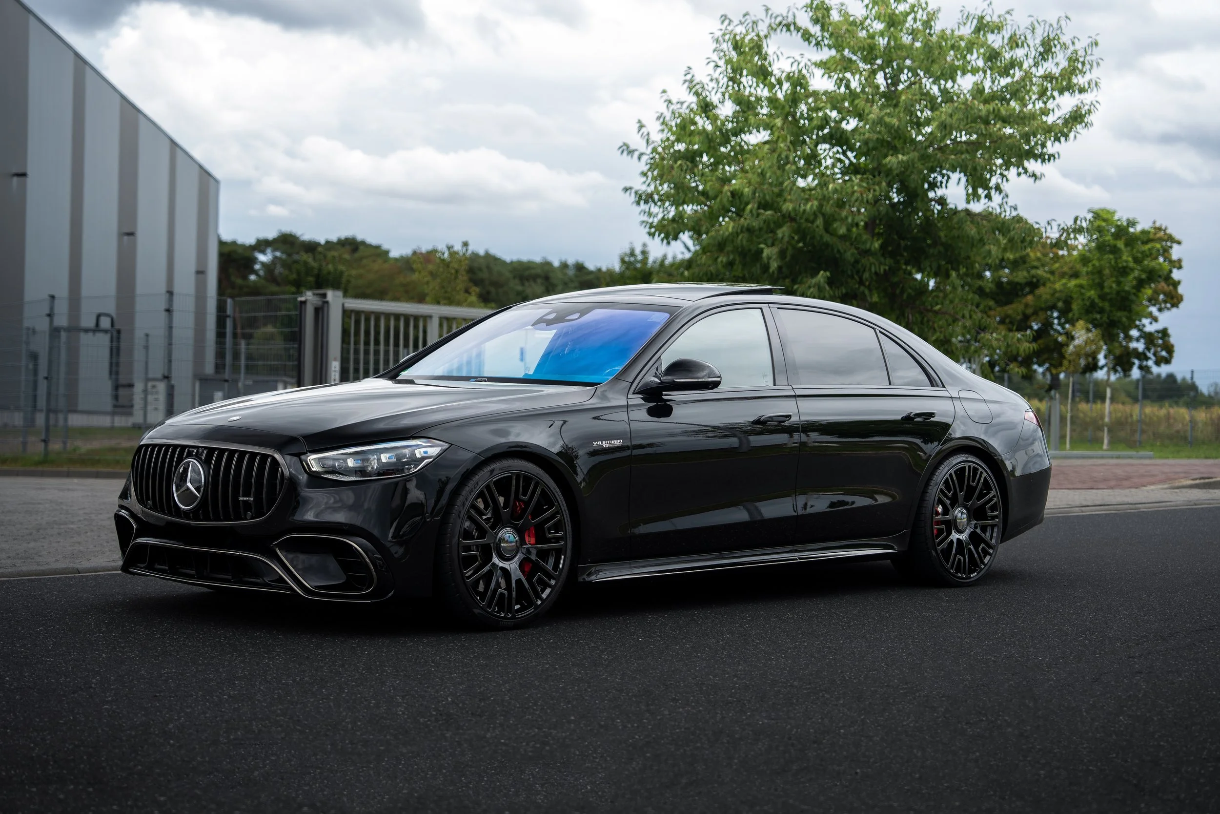 Schwarzer Mercedes-Benz S63 E-Performence auf einer Straße mit Bäumen im Hintergrund.