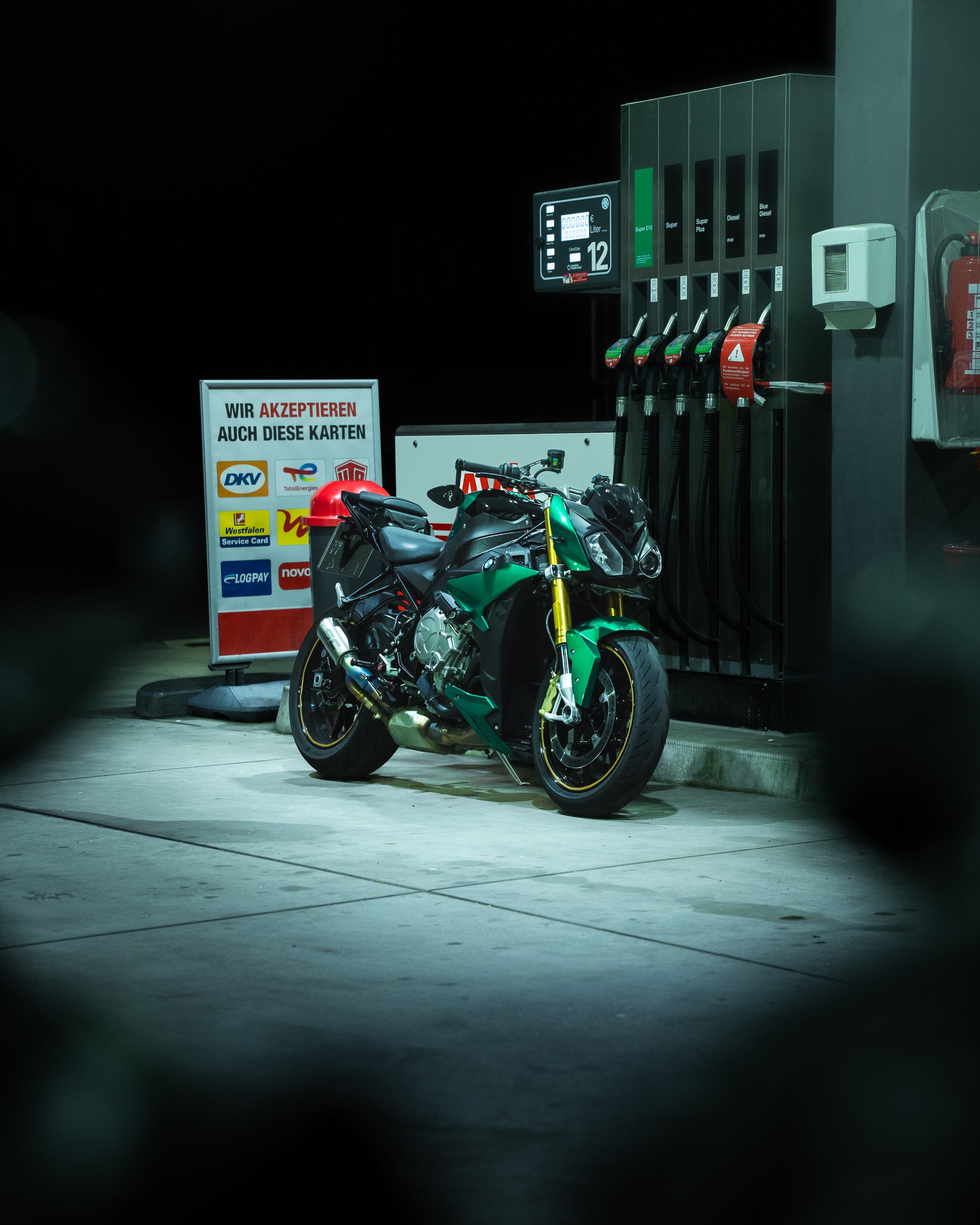 BMW S1000R an Zapfsäule an einer Tankstelle bei Nacht.