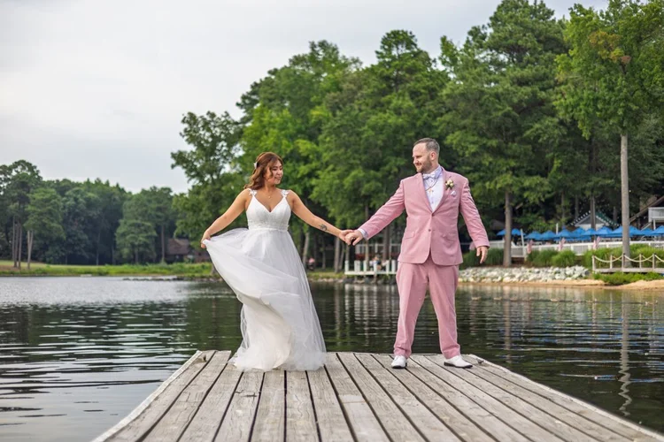 Camille and Kevin sharing a wedding portrait on a waterfront dock.