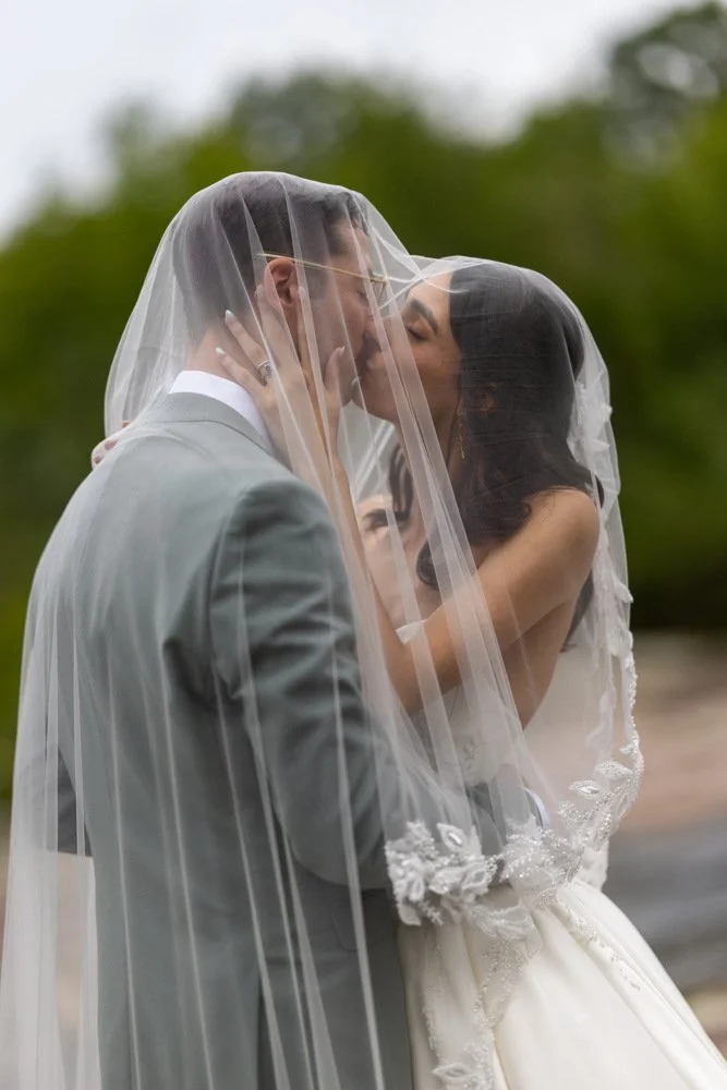 Jenai and Michael sharing a kiss beneath her wedding veil.