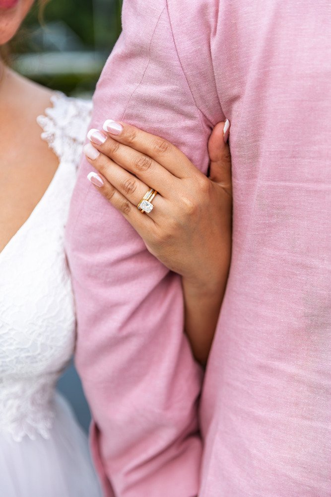 Camille’s hand and wedding ring resting on Kevin’s pink suit jacket.
