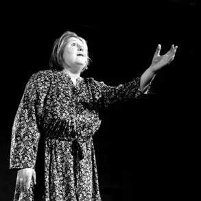Woman singing on stage with one hand raised