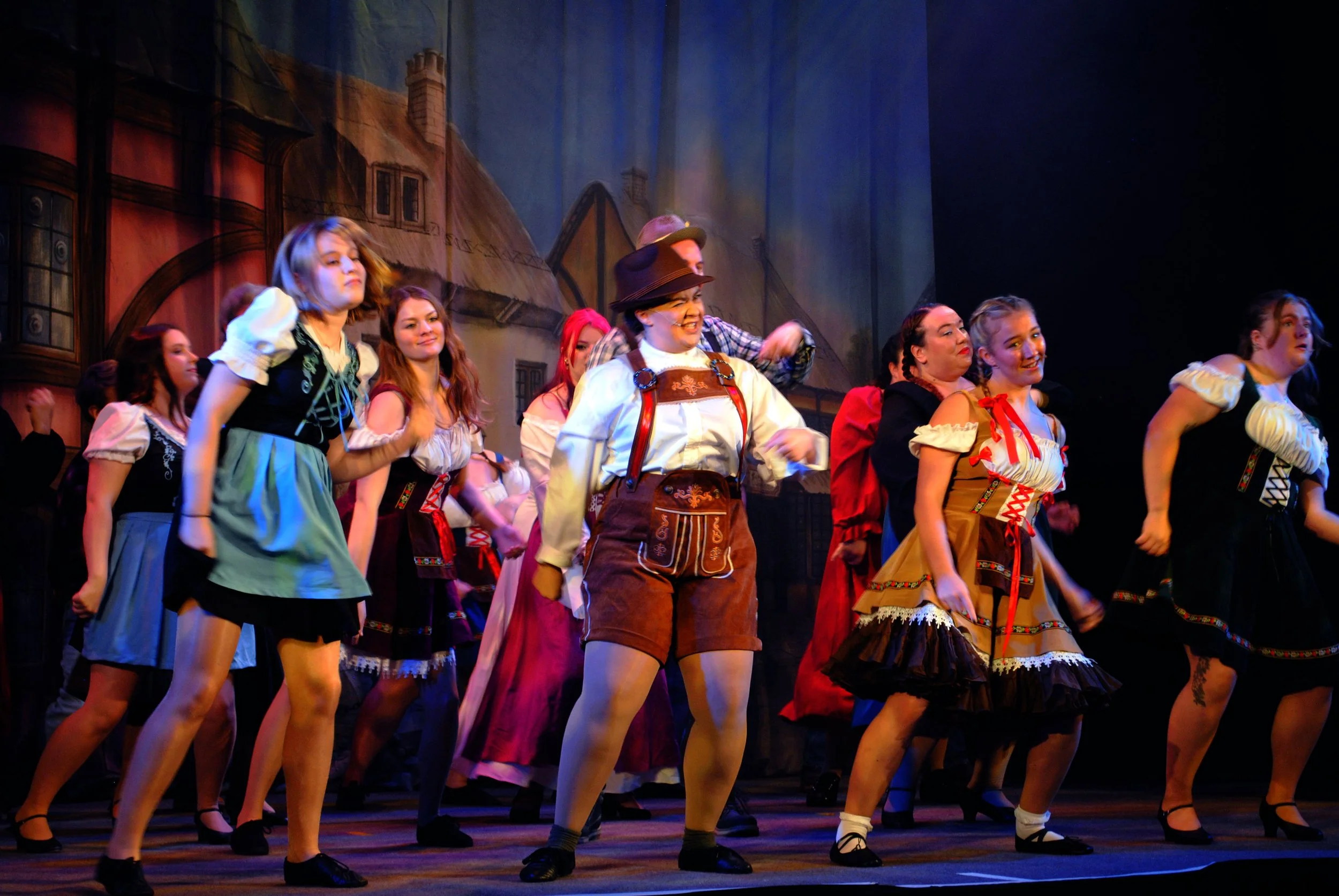 A group of performers dressed in traditional European folk costumes during a stage performance.