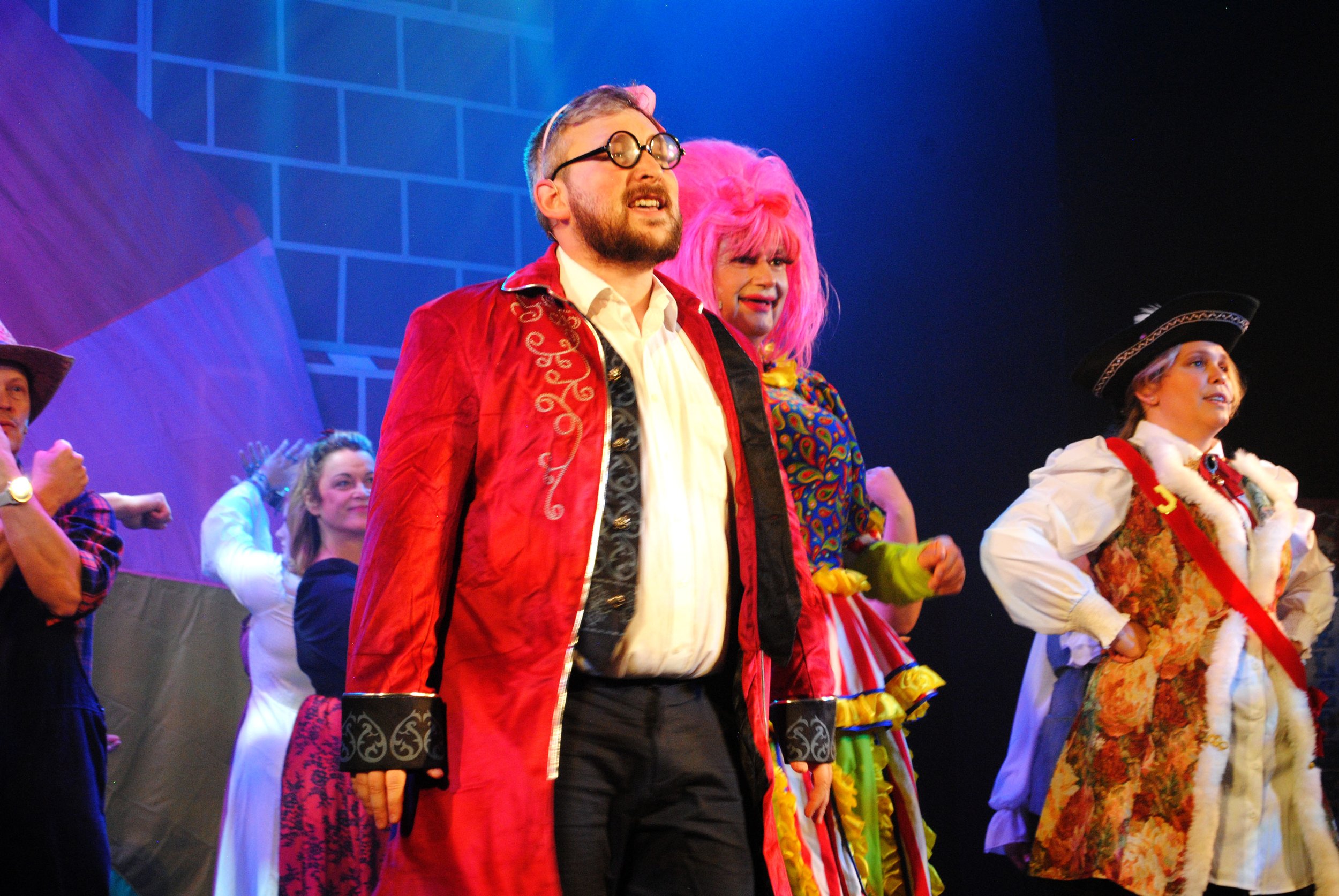 People dressed in colorful costumes on stage during a theatrical performance.