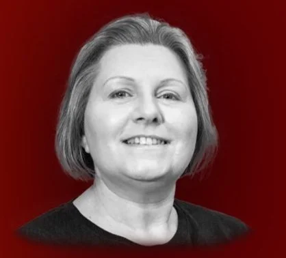 A black and white portrait of a woman with short hair, smiling, against a red background.