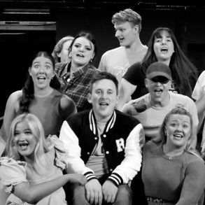 Group of eight young people smiling and laughing together.