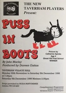 A poster for a school play titled 'Puss in Boots', presented by The New Taverham Players, featuring a drawing of a black cat with a white face and looking like a puppet in boots, against a white background.