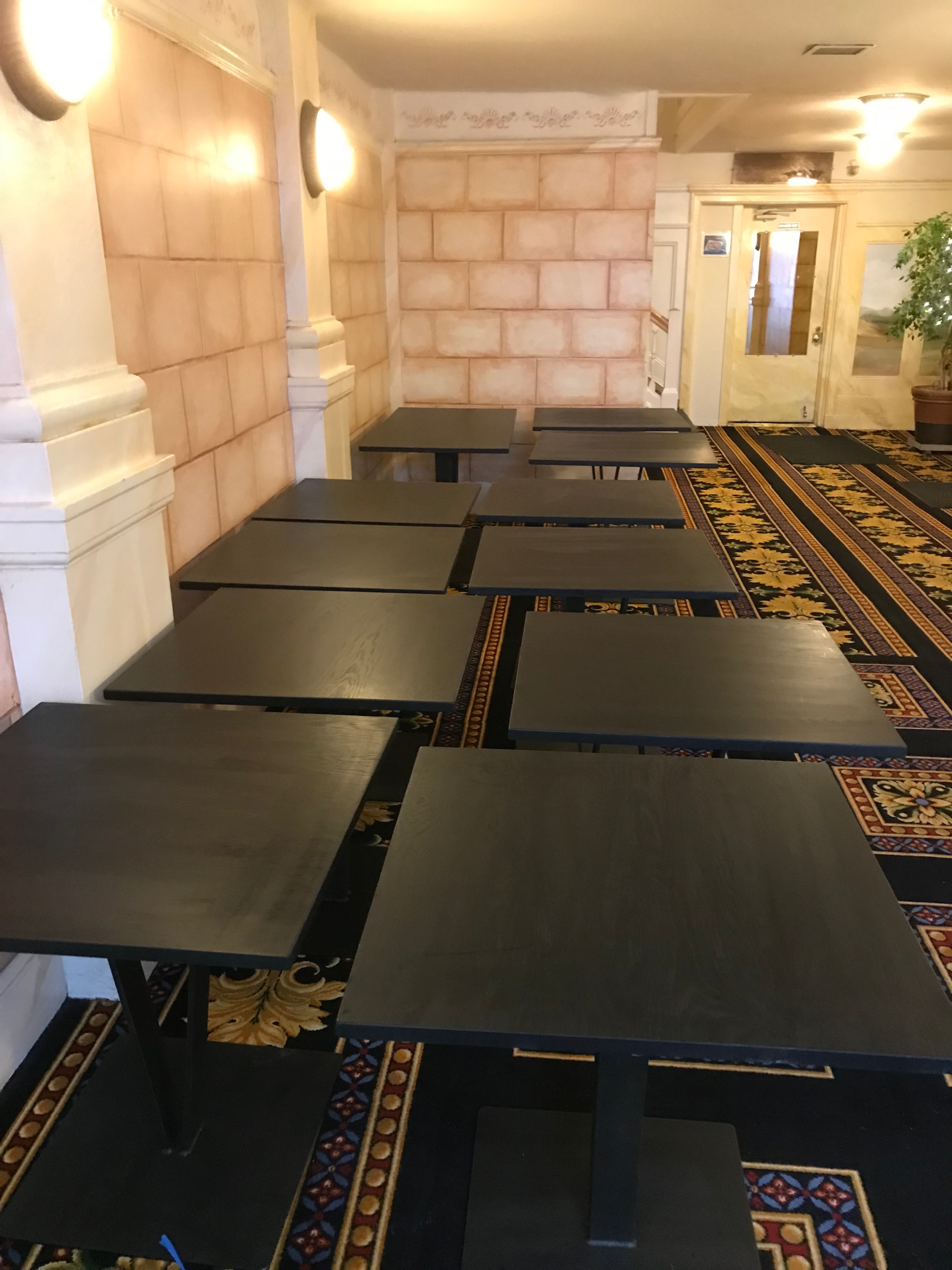 Many custom made dining tables up against a wall.
