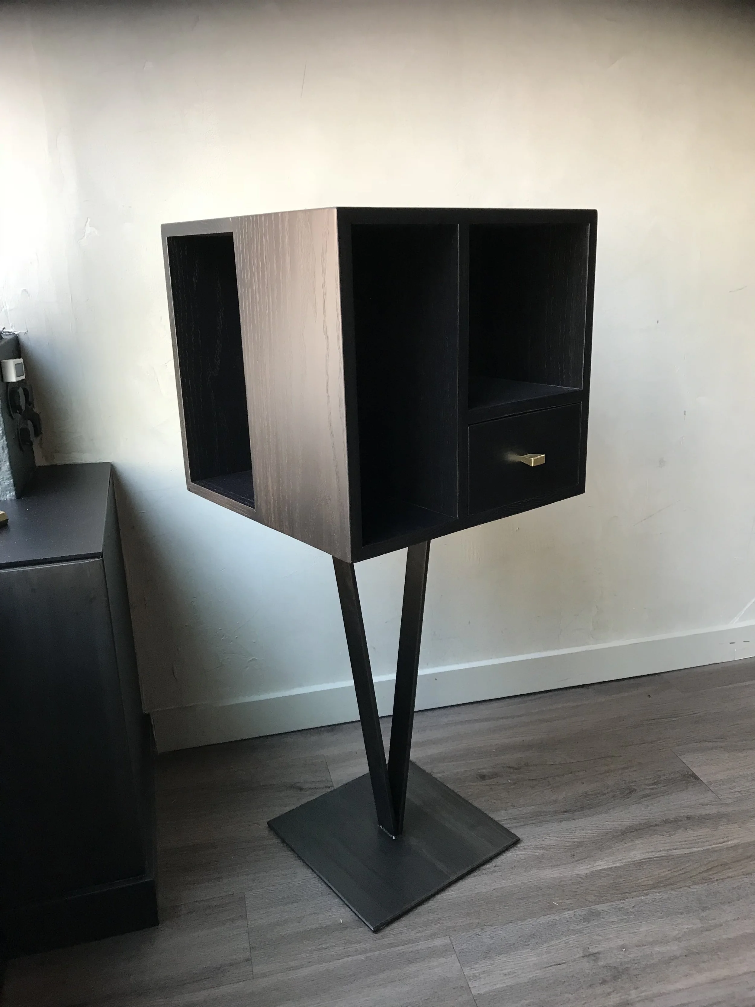 A cube storage/display stand with thin metal legs.