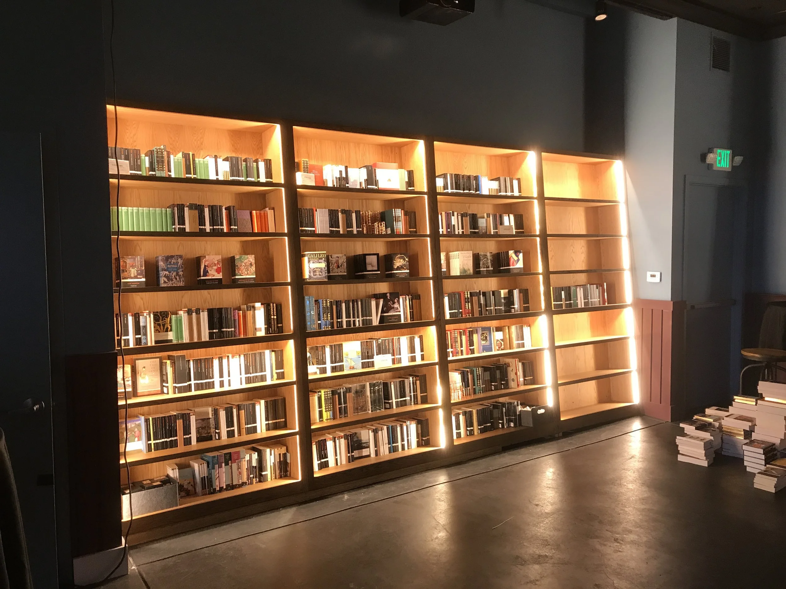 4 large shelving areas designed for holding books, the edges of the shelves area lite up with strip lights.