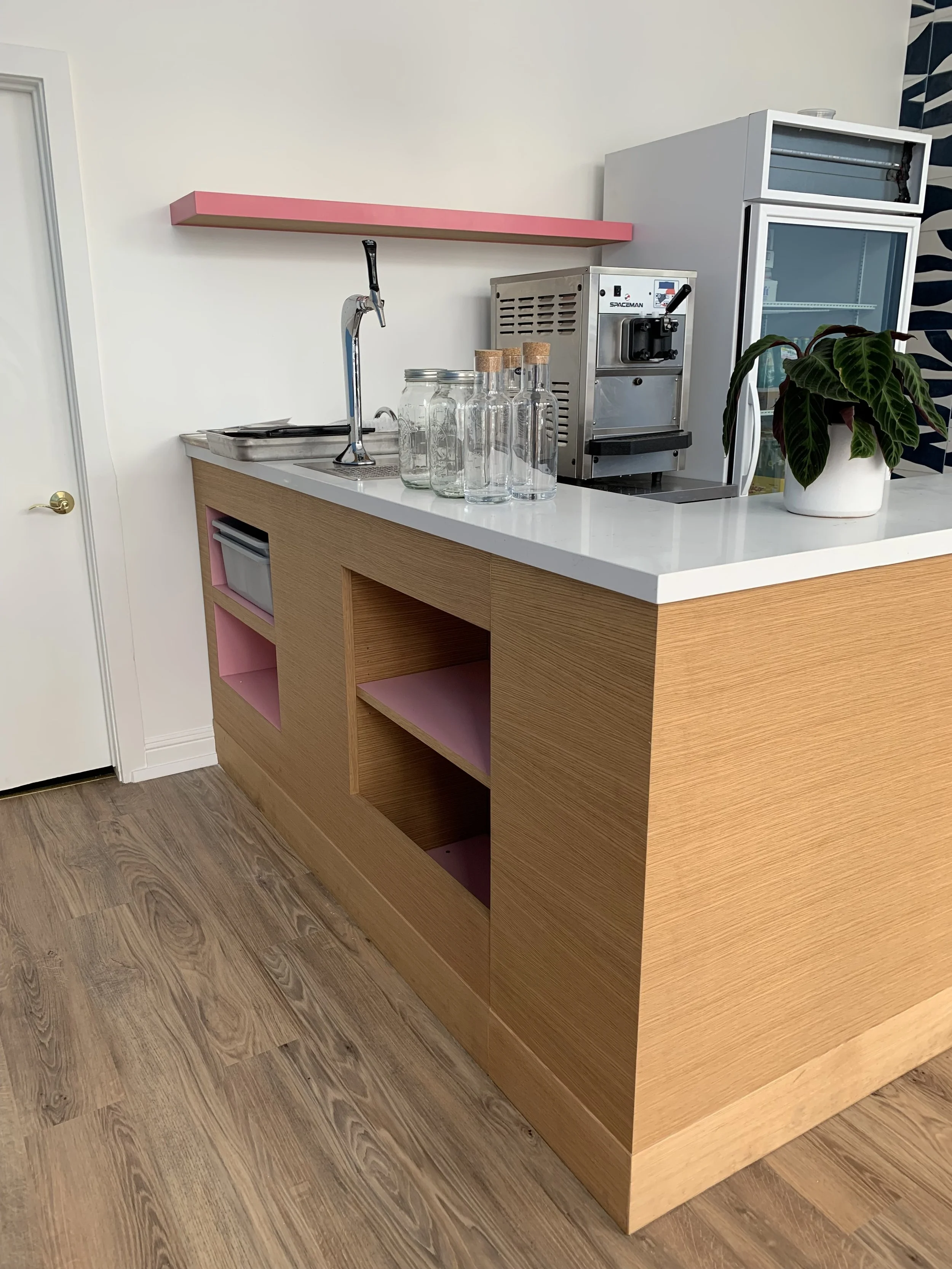 Side view of a large L shaped counter with a wooden base and a white plastic counter top.