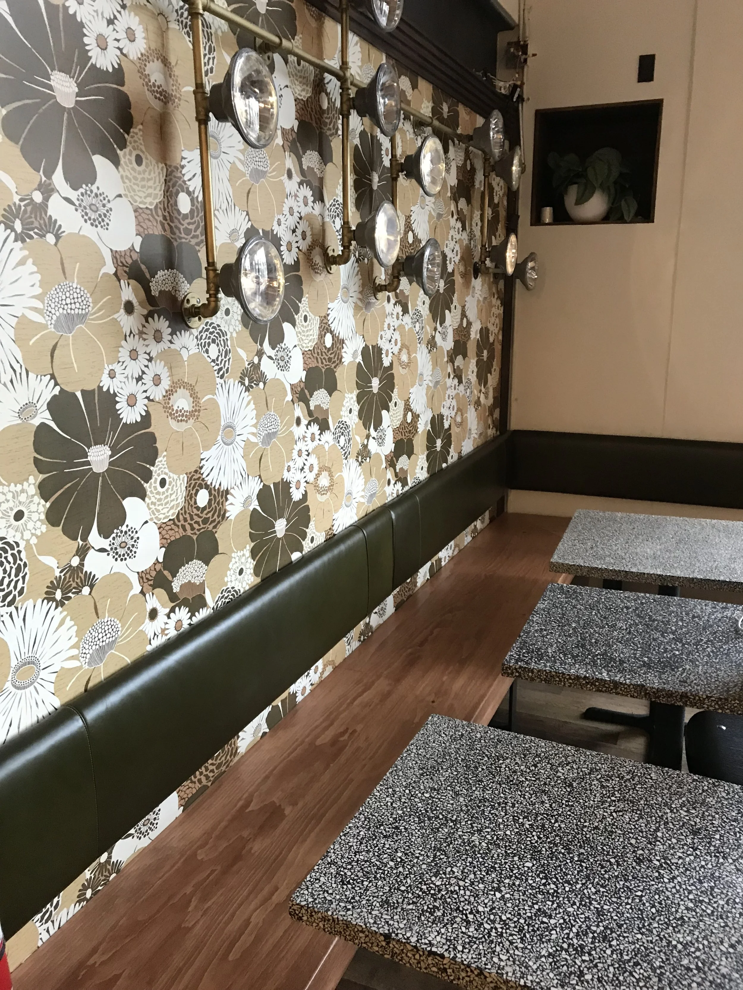A close up of a square shaped seating area with wooden seating and 3 tables with marble like table tops.
