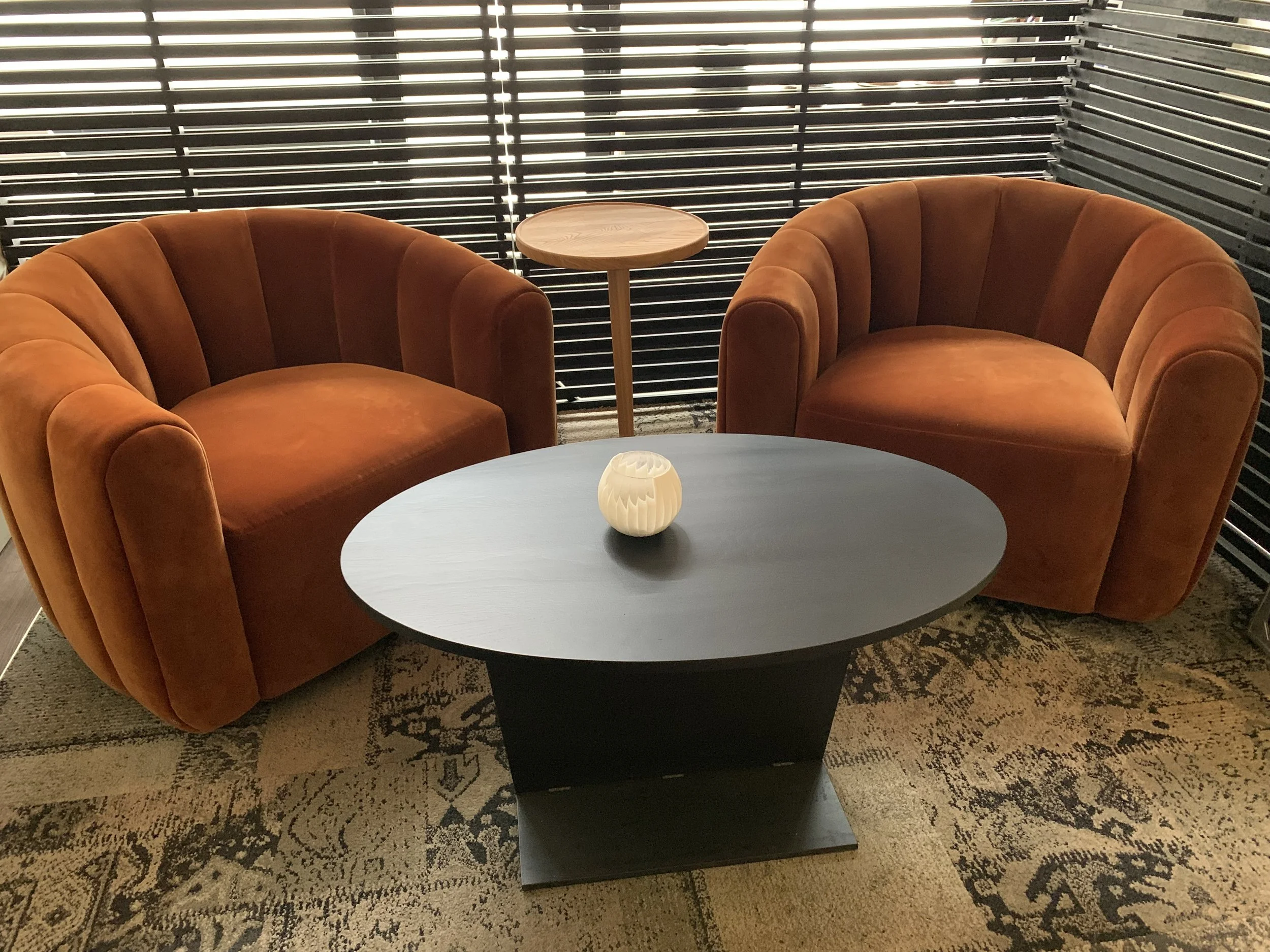 A round coffee table with 2 sofa chairs around the table.