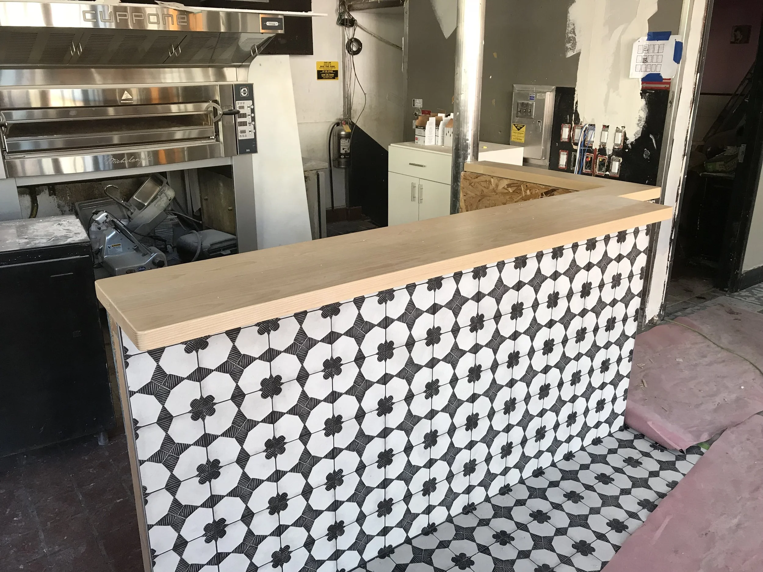 Wooden bar counter with star tiling along the front, merging into the floor design.