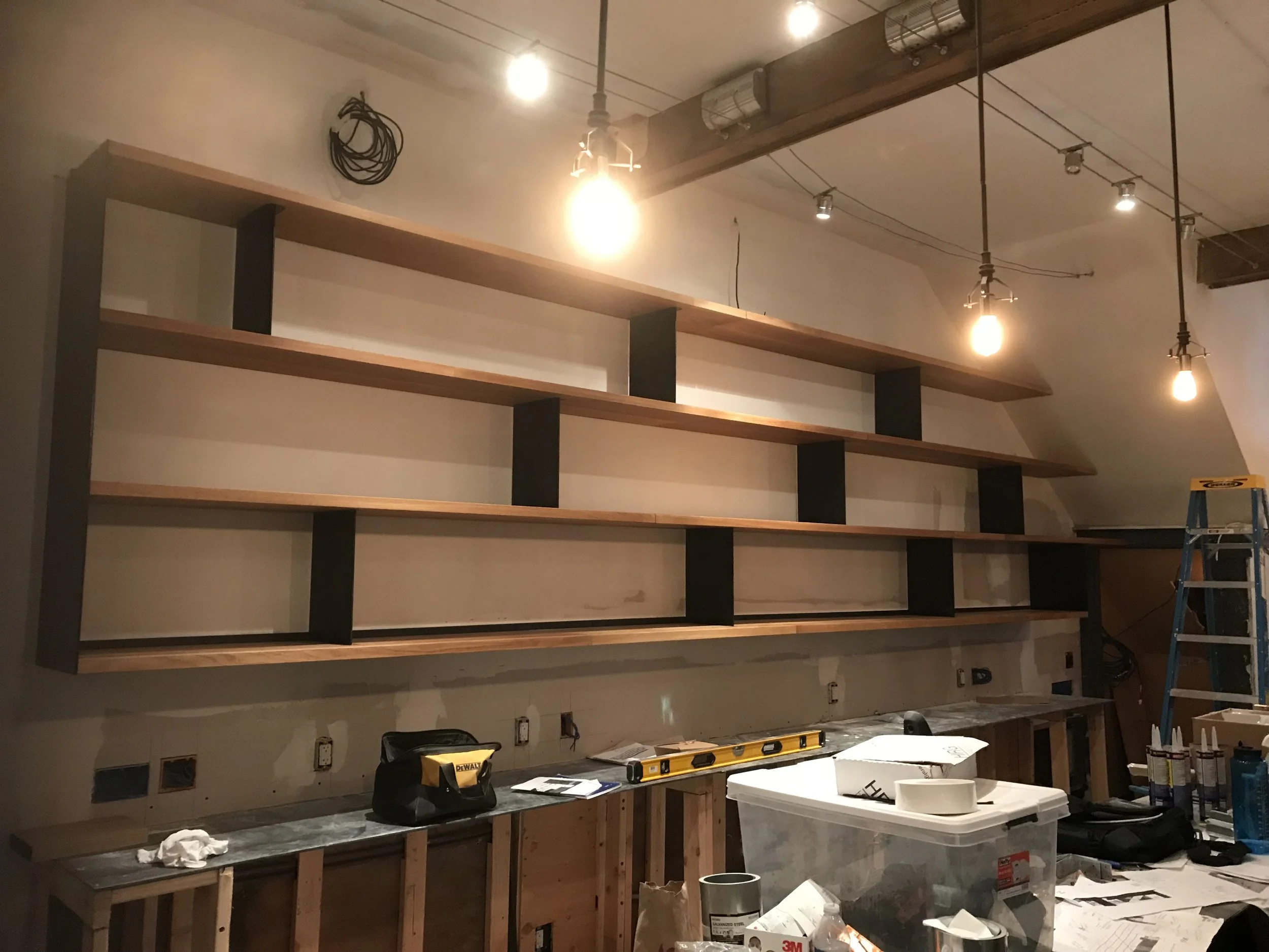 Custom built wooden shelving designed to fit the wall with a slanted roof on the right side.