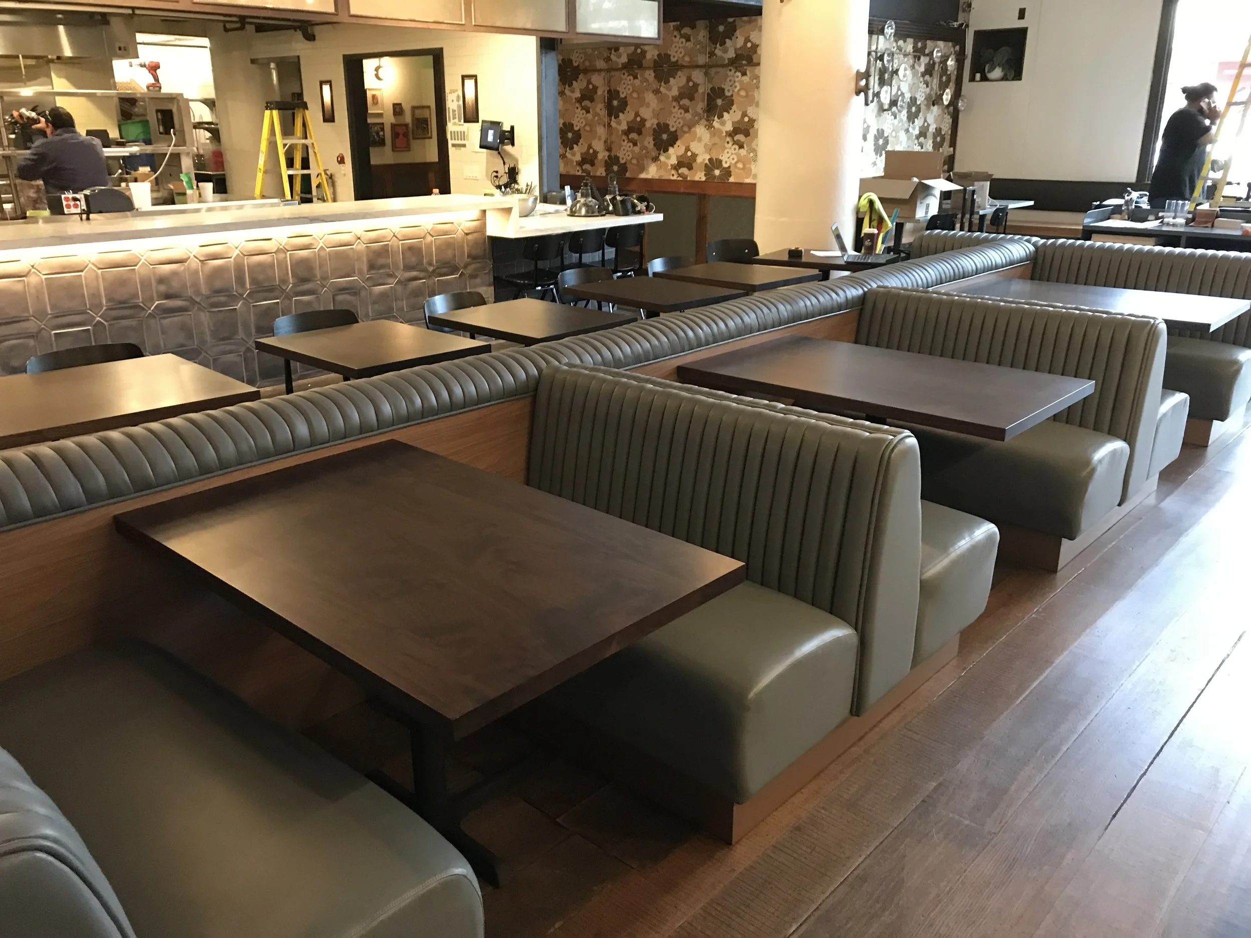 Leather booths with wooden tables are placed down the centre of the restaurant. On the other side of the booths are smaller seating tables with square table tops.