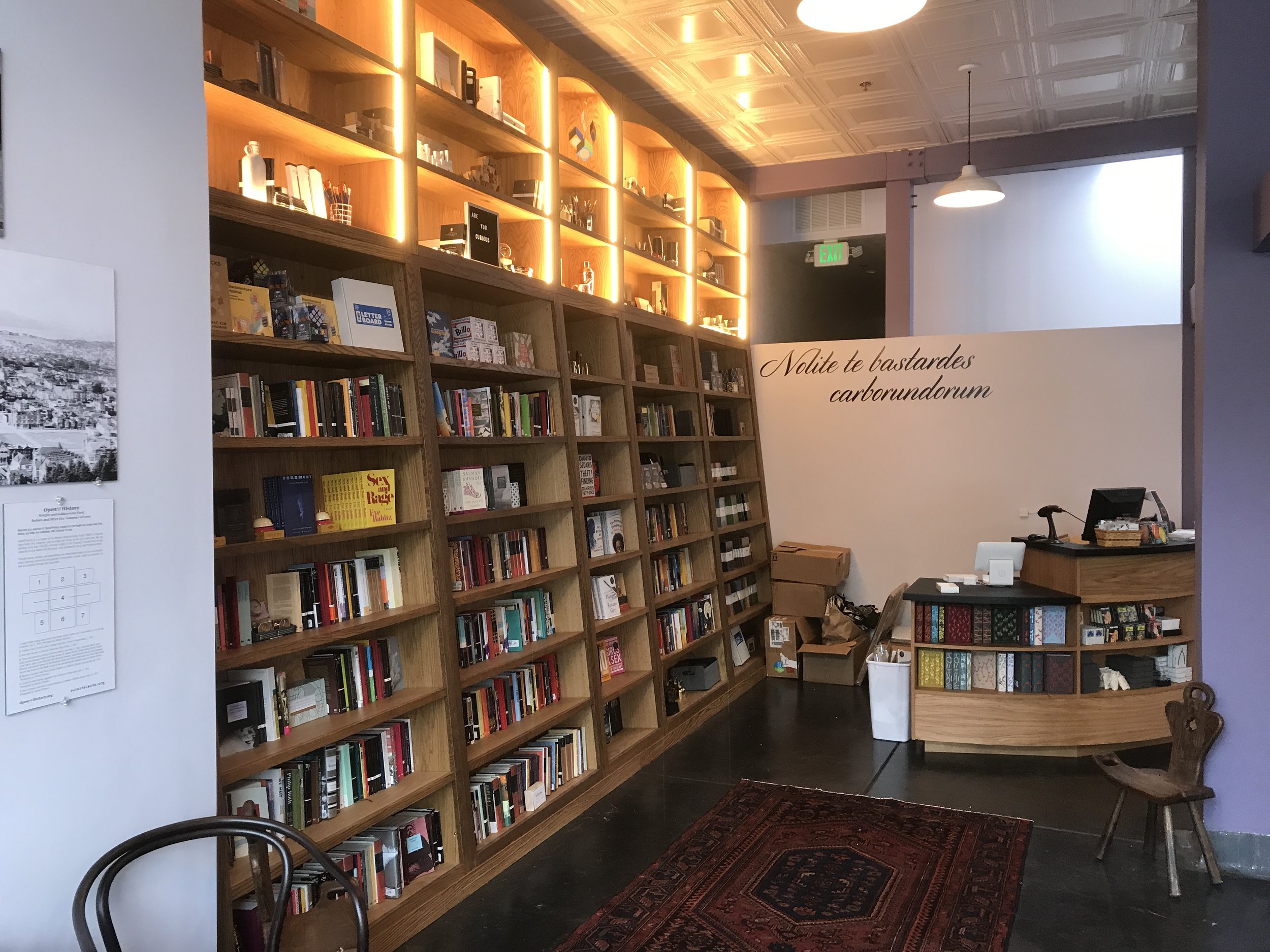 Many rows of shelving for books with smaller shelves above for displays and holding books. The smaller top row is lite up with stripe lights.