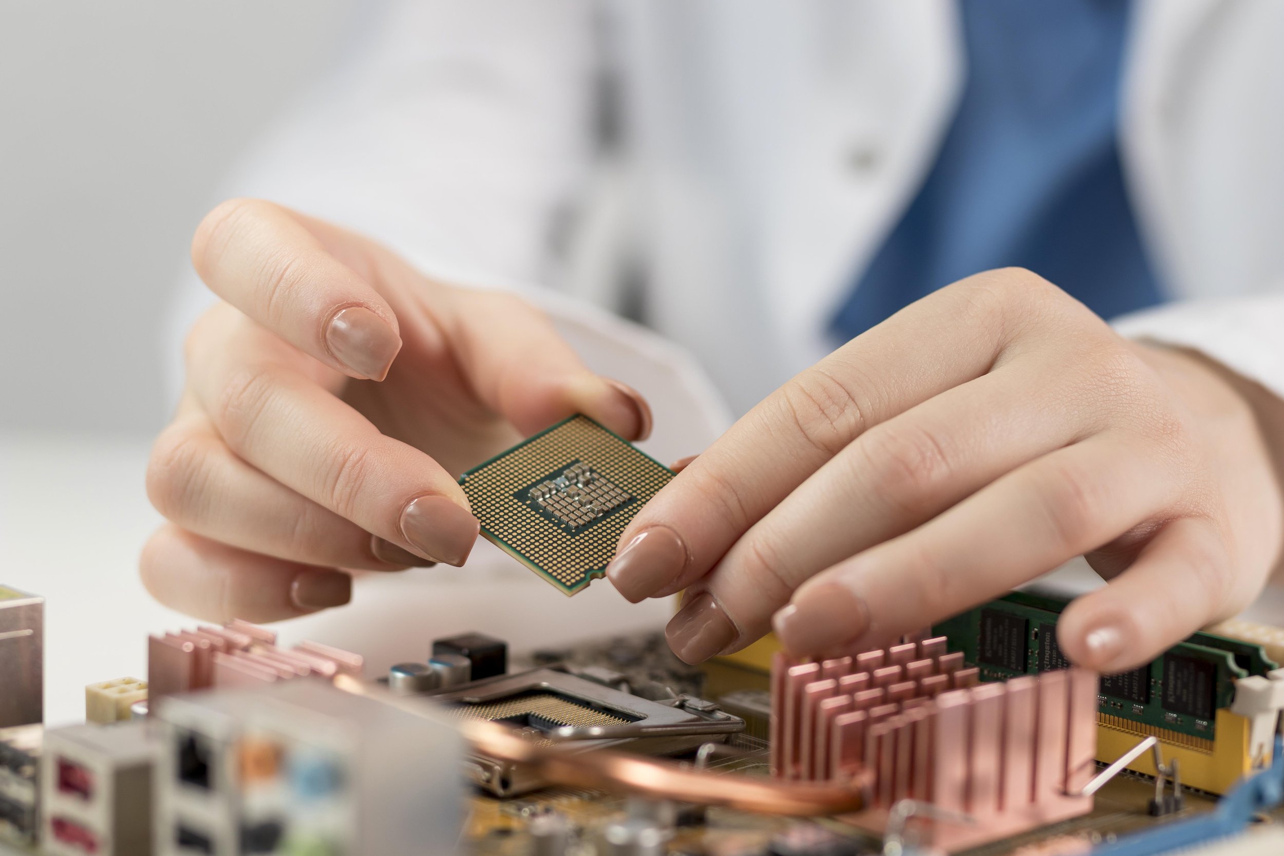 Person holding a computer processor over a motherboard with various components.