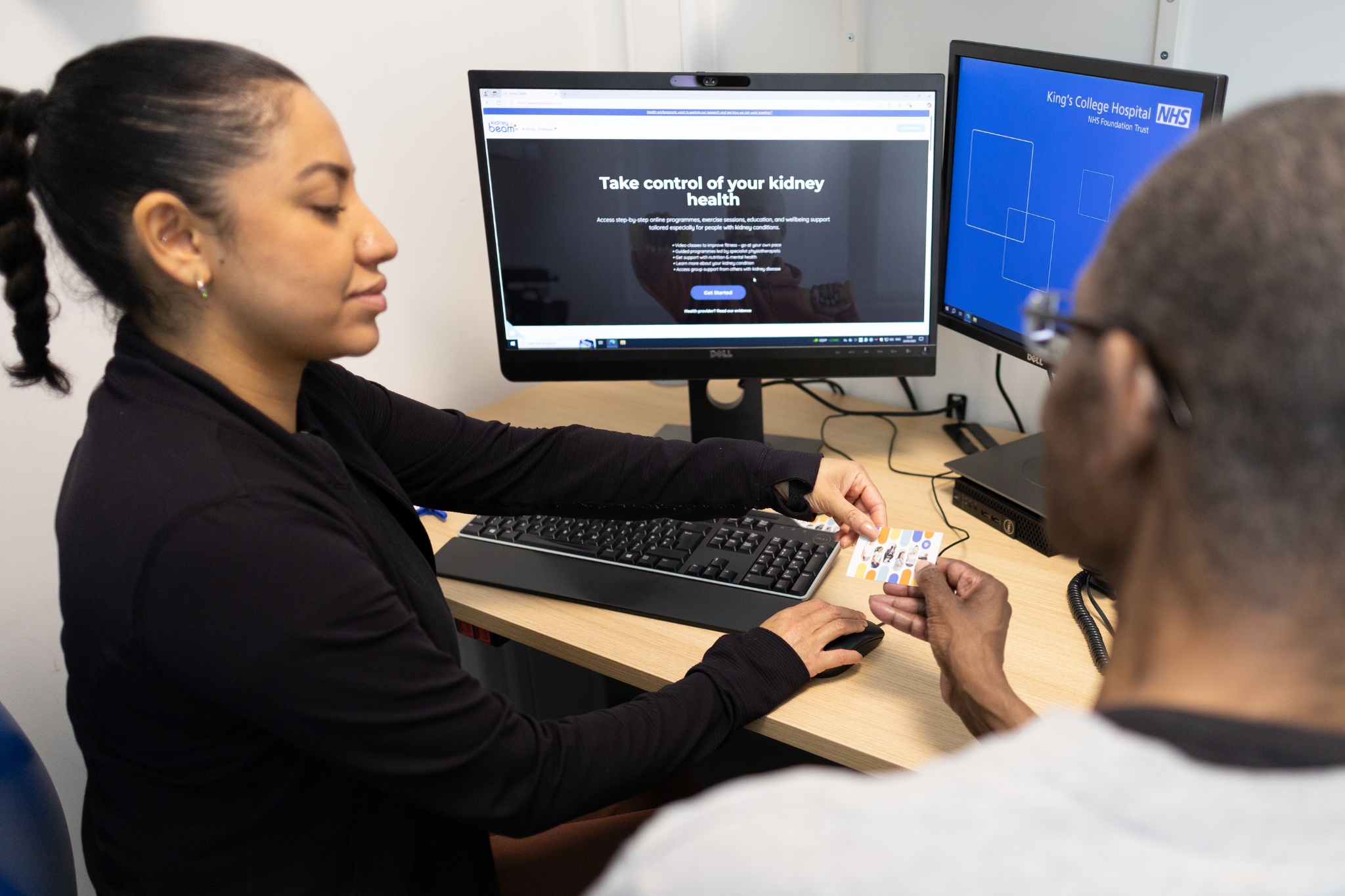 A clinician showing a patient Kidney Beam at a desk