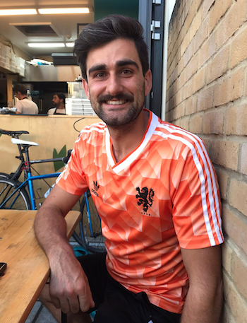 Christy smiles at the camera wearing a bright orange sports top