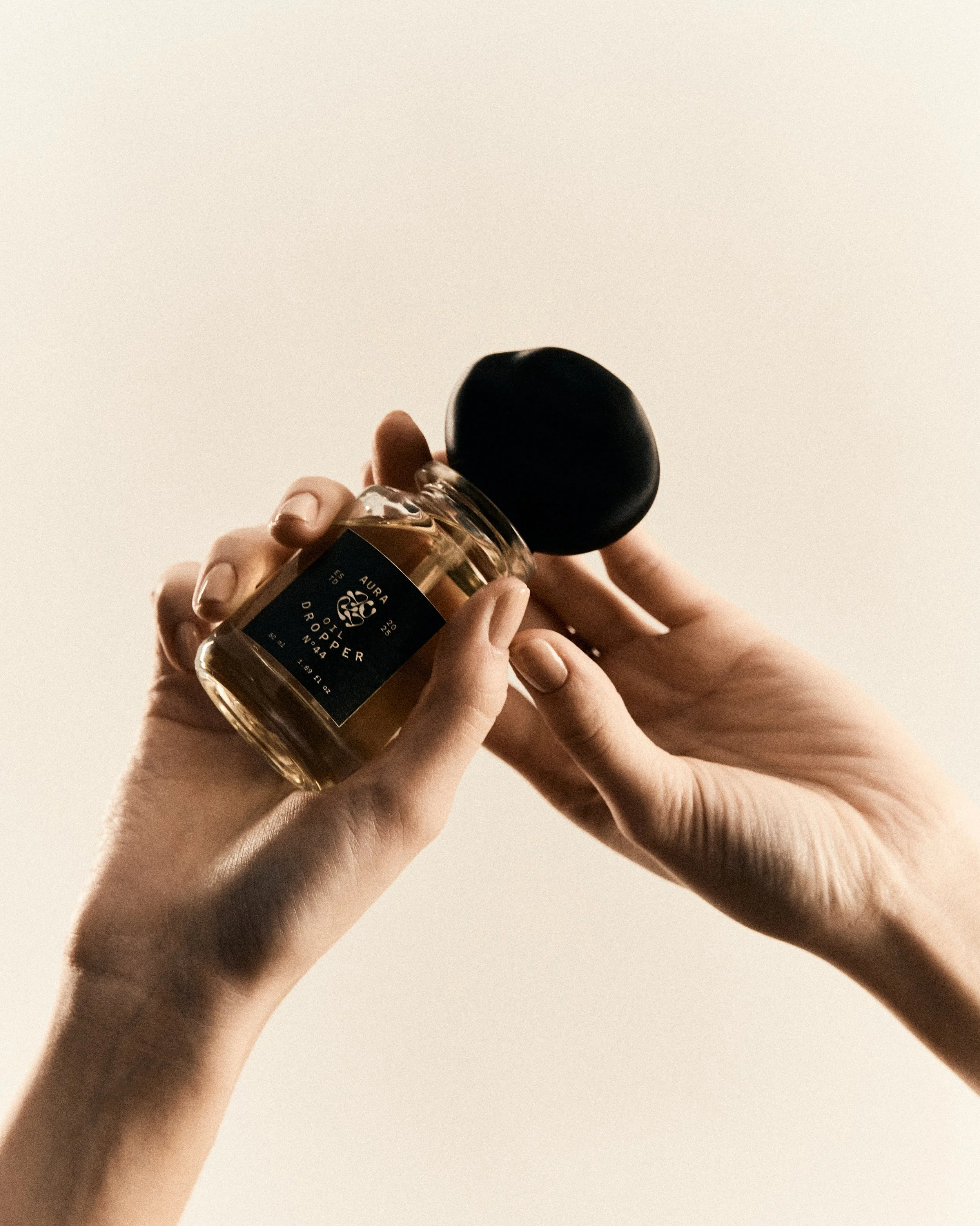 Mani che tengono un piccolo flacone di profumo con un tappo nero