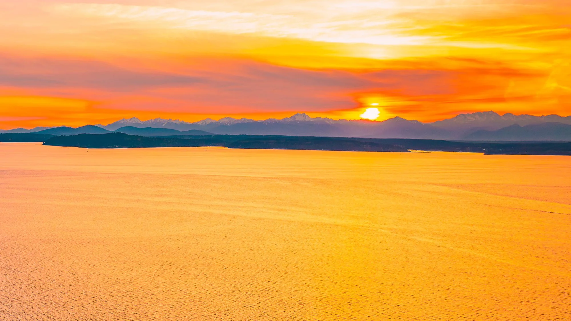 Sunset over a body of water with mountains and colorful sky