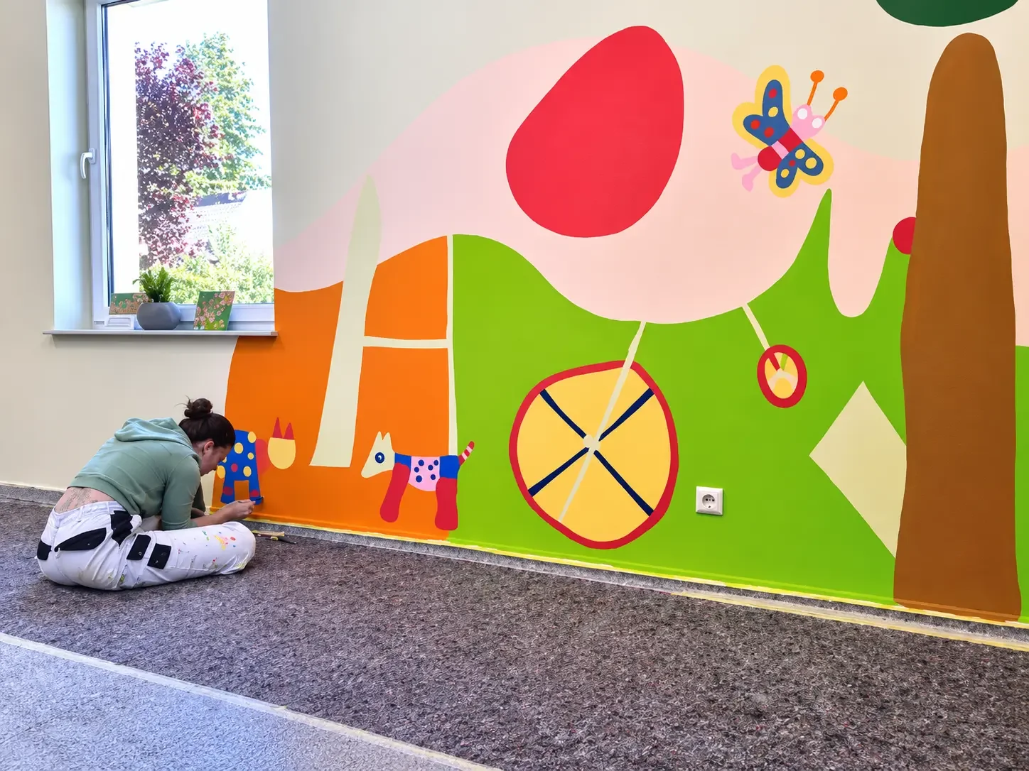 Klientin der IGZ gestaltet eine farbenfrohe Wandmalerei im Museumscafé des Kunstmuseums Waldviertel