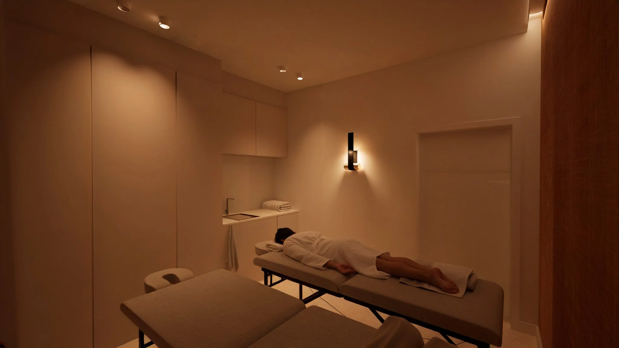 Une personne allongée sur une table de massage dans une salle de spa ou massage, avec un éclairage tamisé et une ambiance chaleureuse.