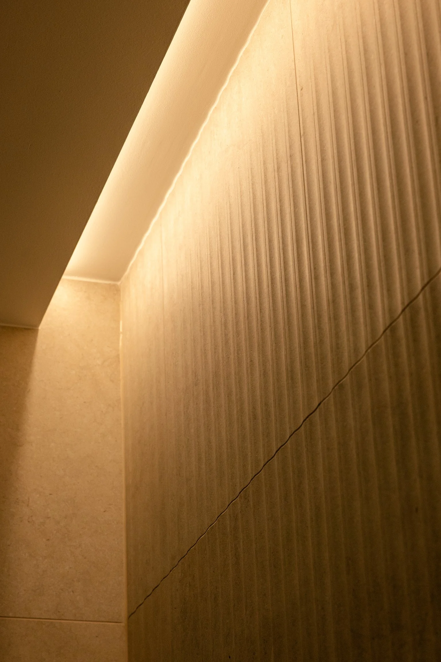Détail d'une surface de plafond et mur en papier peint avec lignes et effets de lumière doucement colorée.  Spa Beroa.