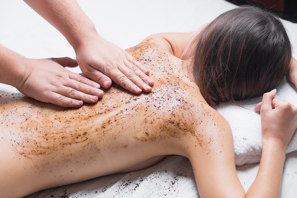 Une personne reçoit un massage au gommage corporel au dos dans un spa.