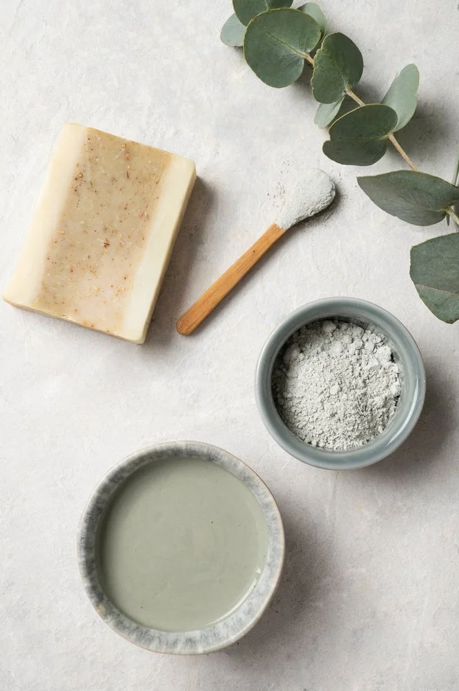 Produits de soins naturels : savon, poudre blanche, huile et branches de eucalyptus.