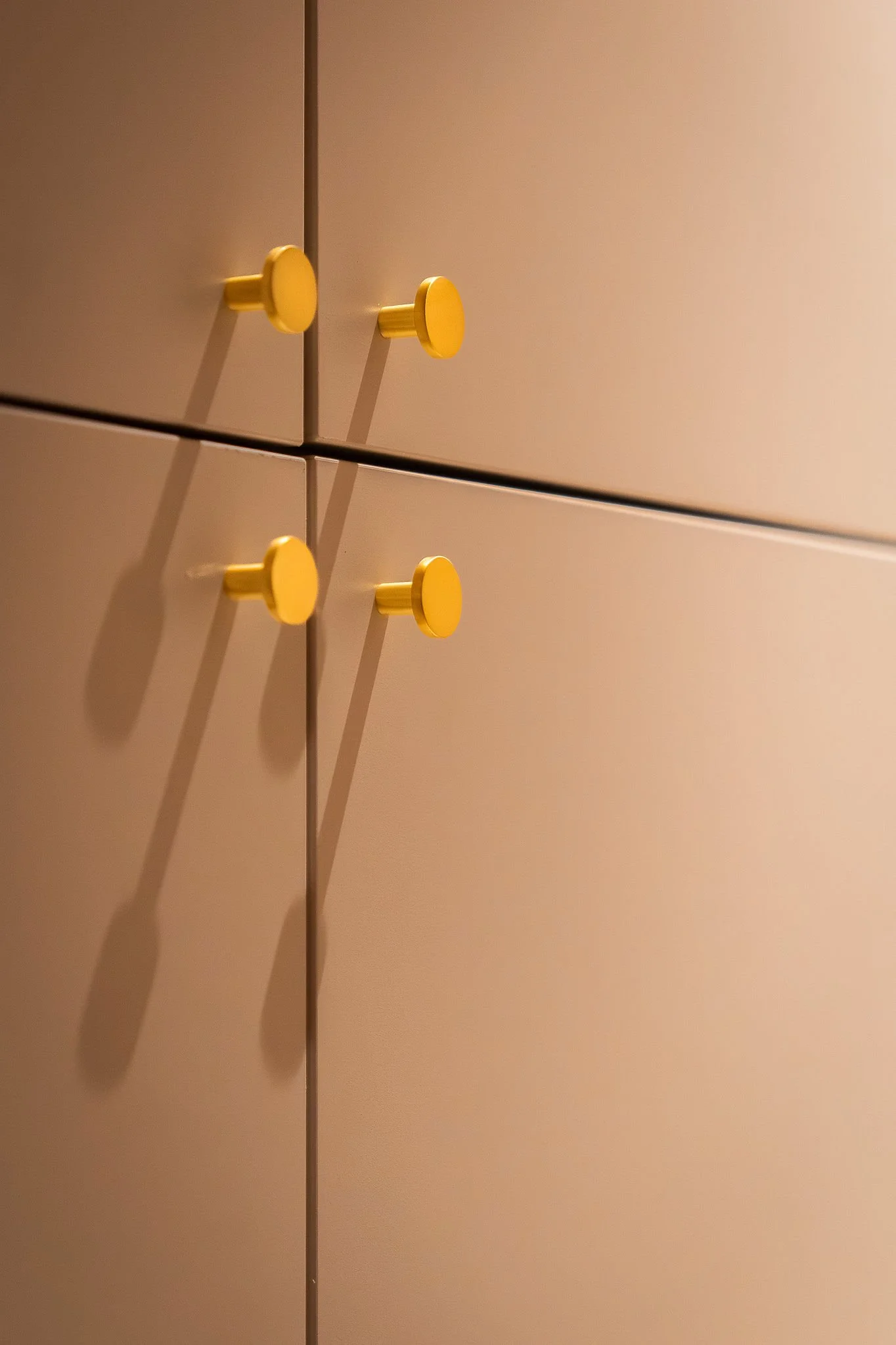 Une armoire beige avec des poignées jaunes.