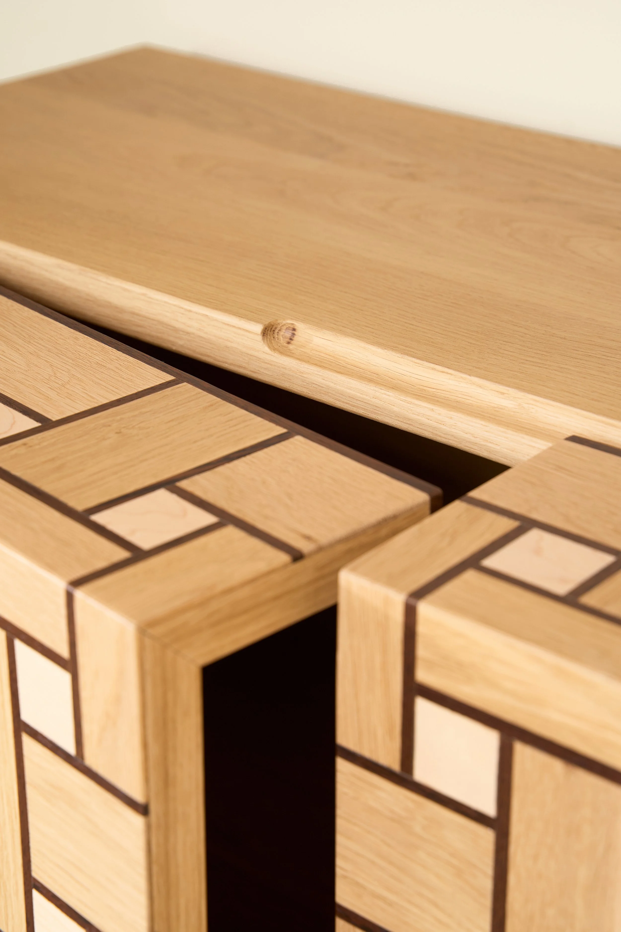 Close-up of a wooden surface with a smooth edge and a rectangular wooden box with a brick-like pattern inlaid on its surface.
