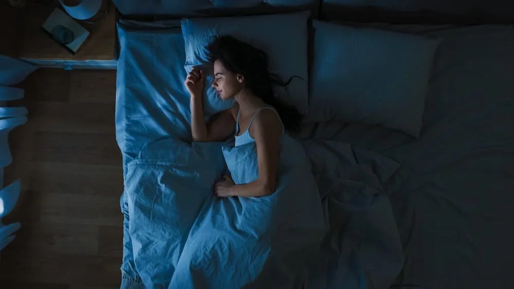 Woman sleeping peacefully in bed, highlighting symptoms and treatment for sleep apnea in women.