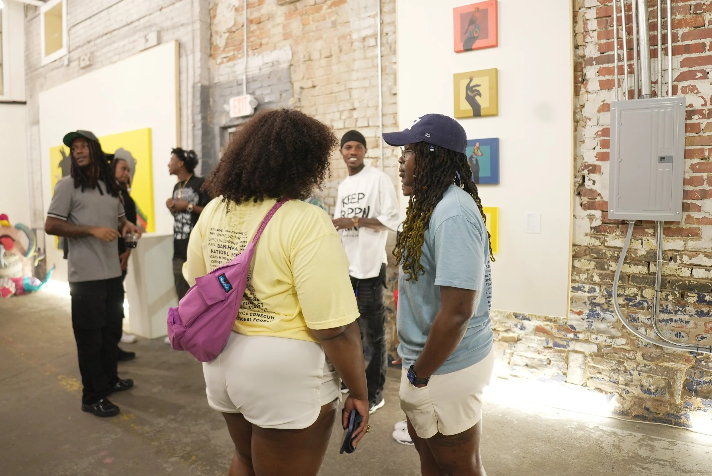 Group of people talking in an art gallery with brick walls and colorful artwork.