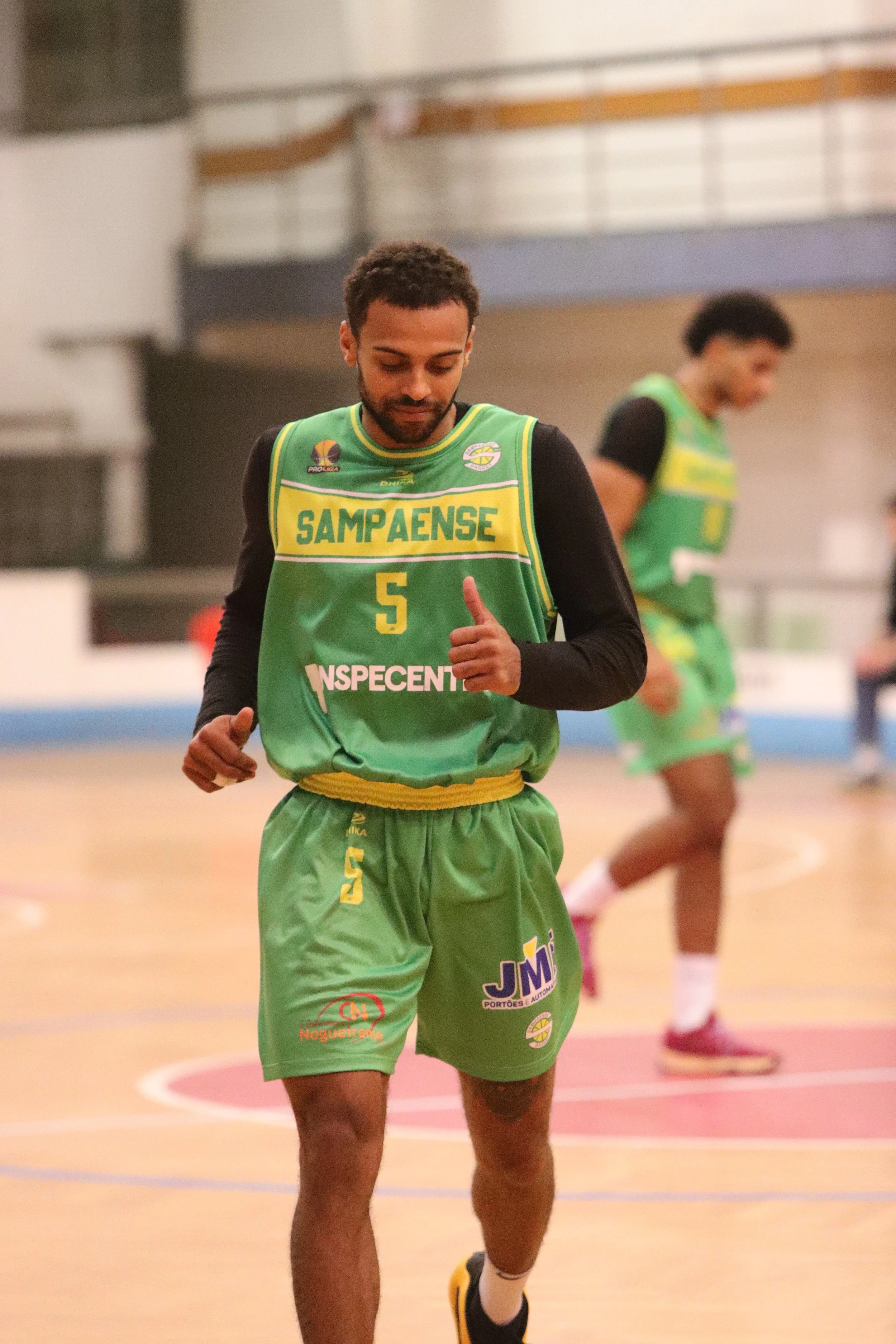 A basketball player in green uniform with the number 5, jogging on the court during a game.