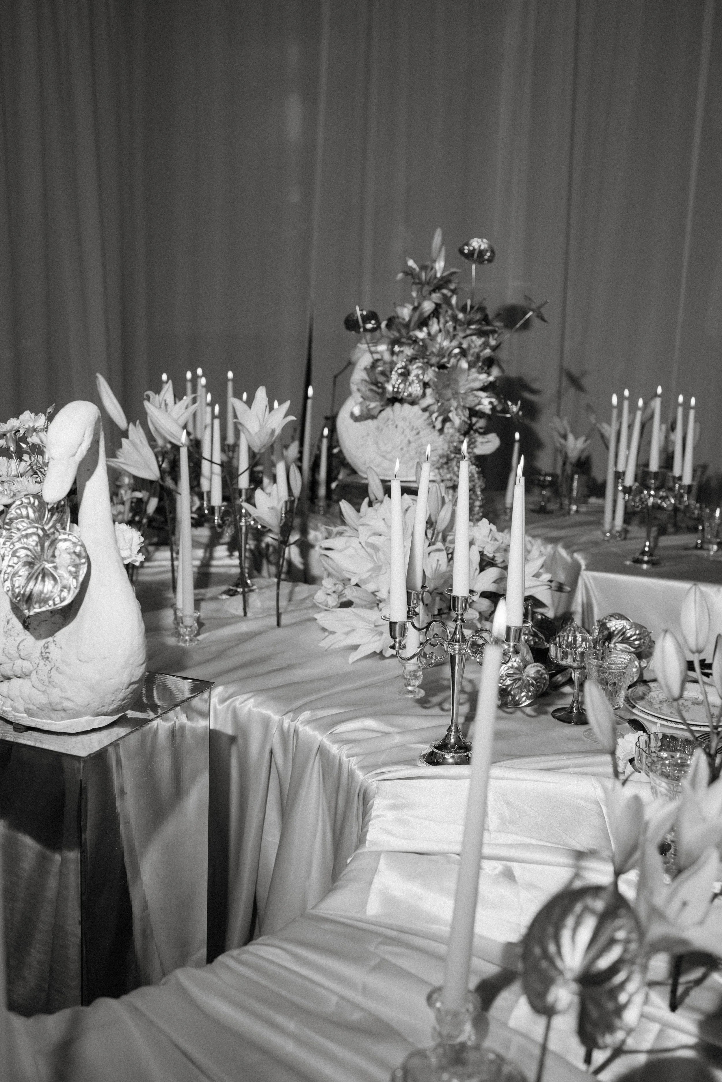 Salle à manger décorée avec des fleurs, bougies et nappes blanches, probablement pour une occasion spéciale.