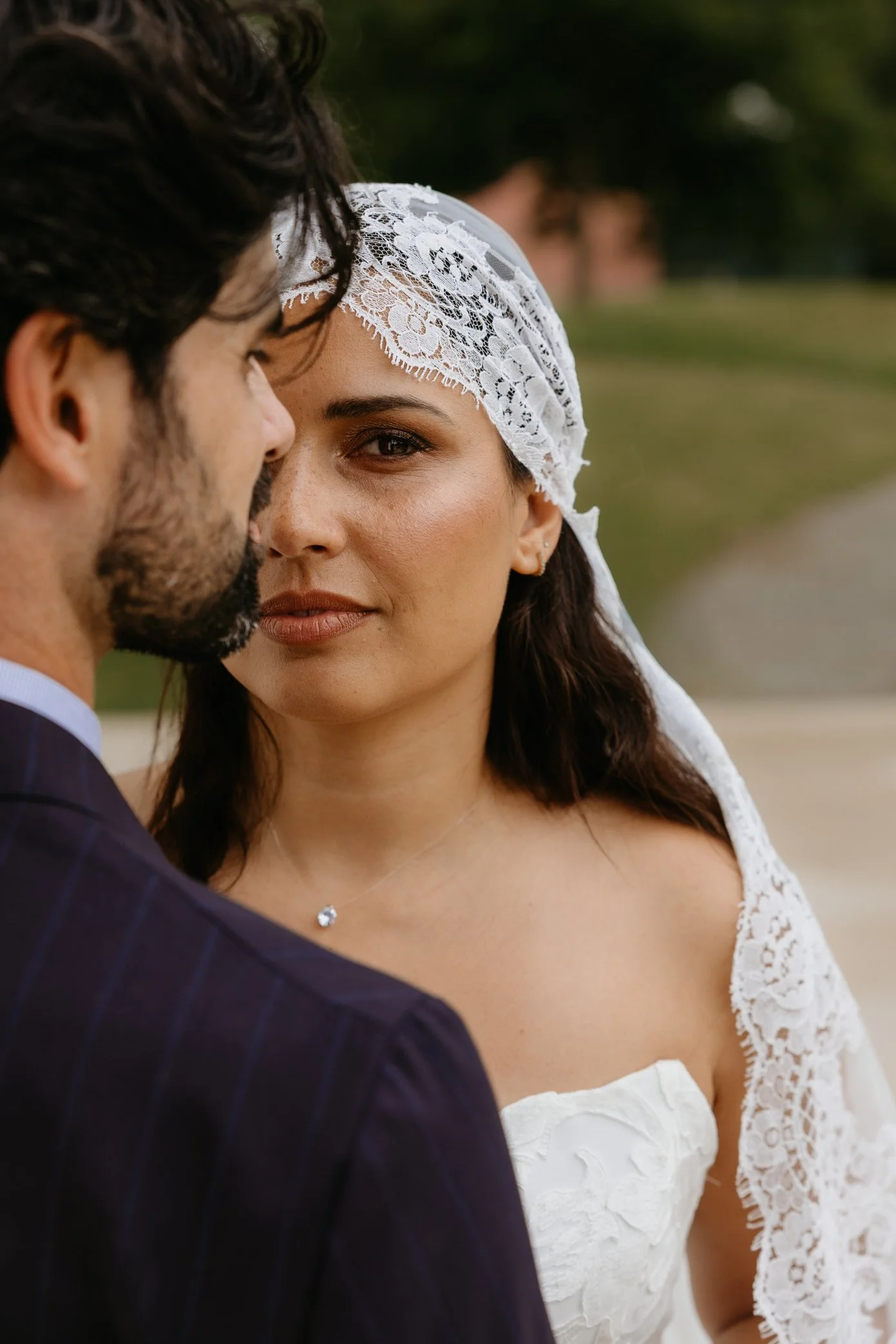 Un couple lors de leur mariage, la femme porte une robe blanche en dentelle avec un voile blanc, et l'homme porte un costume à rayures.