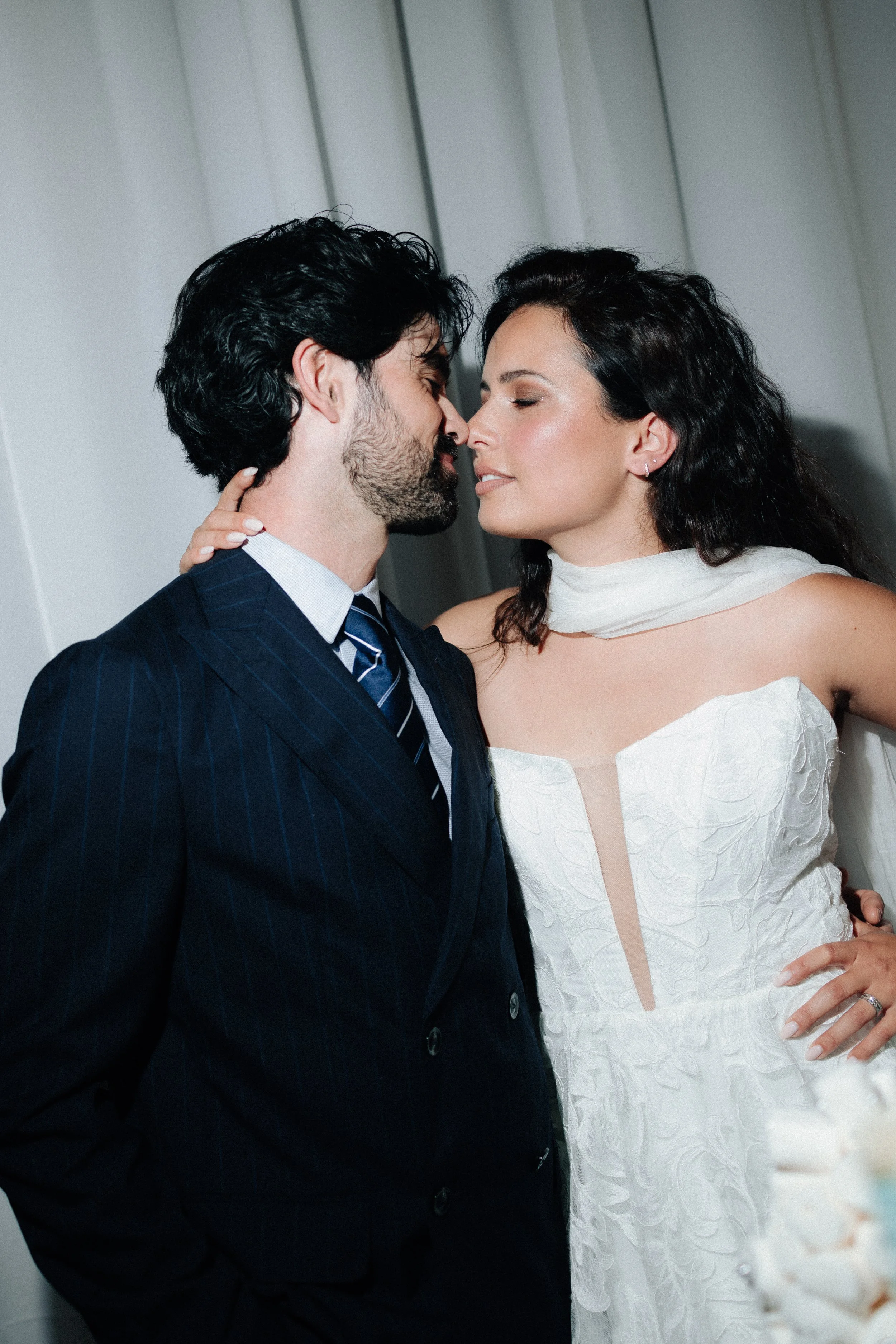 Un couple en costume et robe de mariage en train de s'embrasser de près.