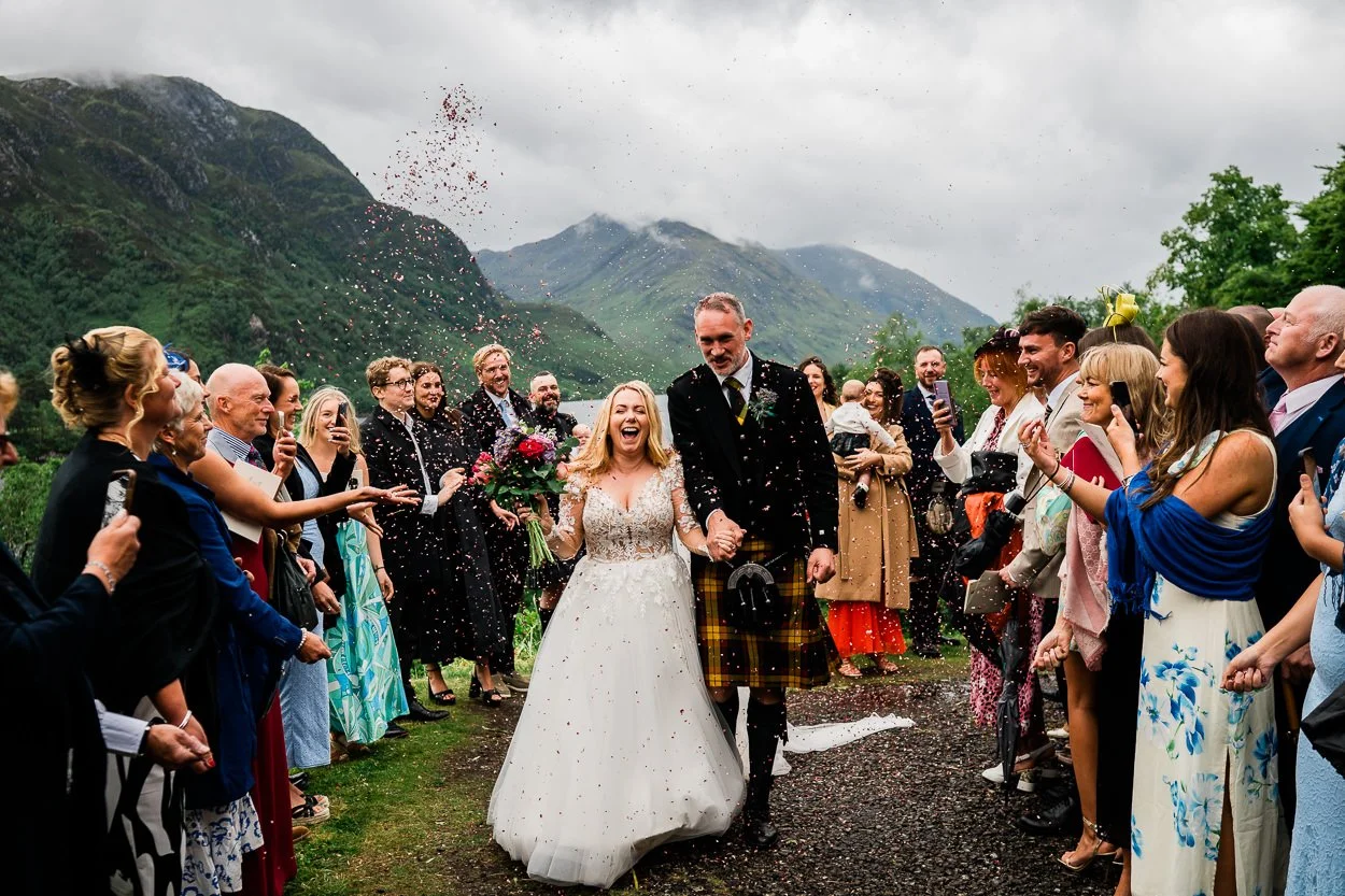 Bride-and-groom-walking-through-confetti-Glenfinnan-church