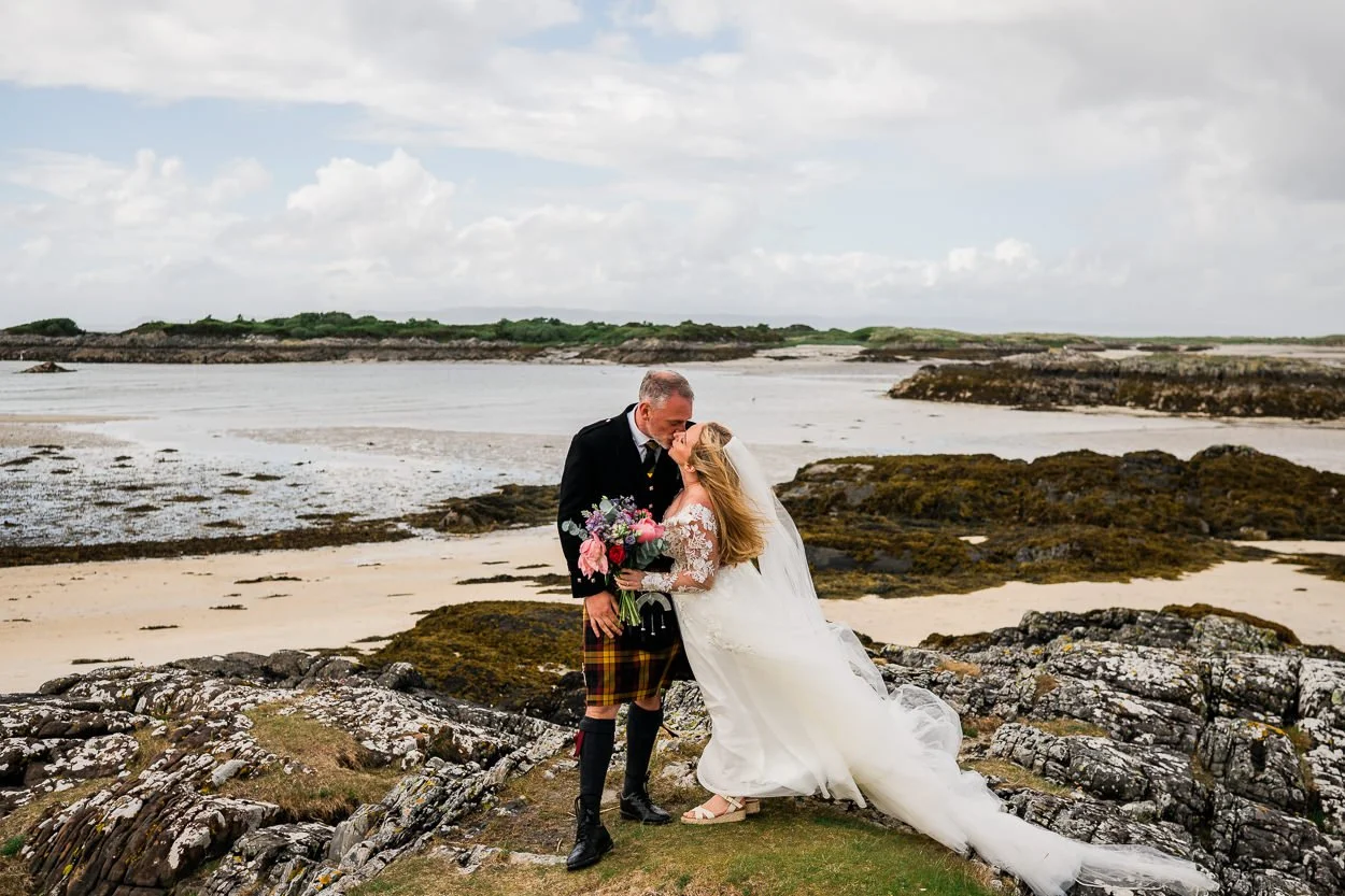 Bride and groom embracing with sweeping Scottish coastline in the background