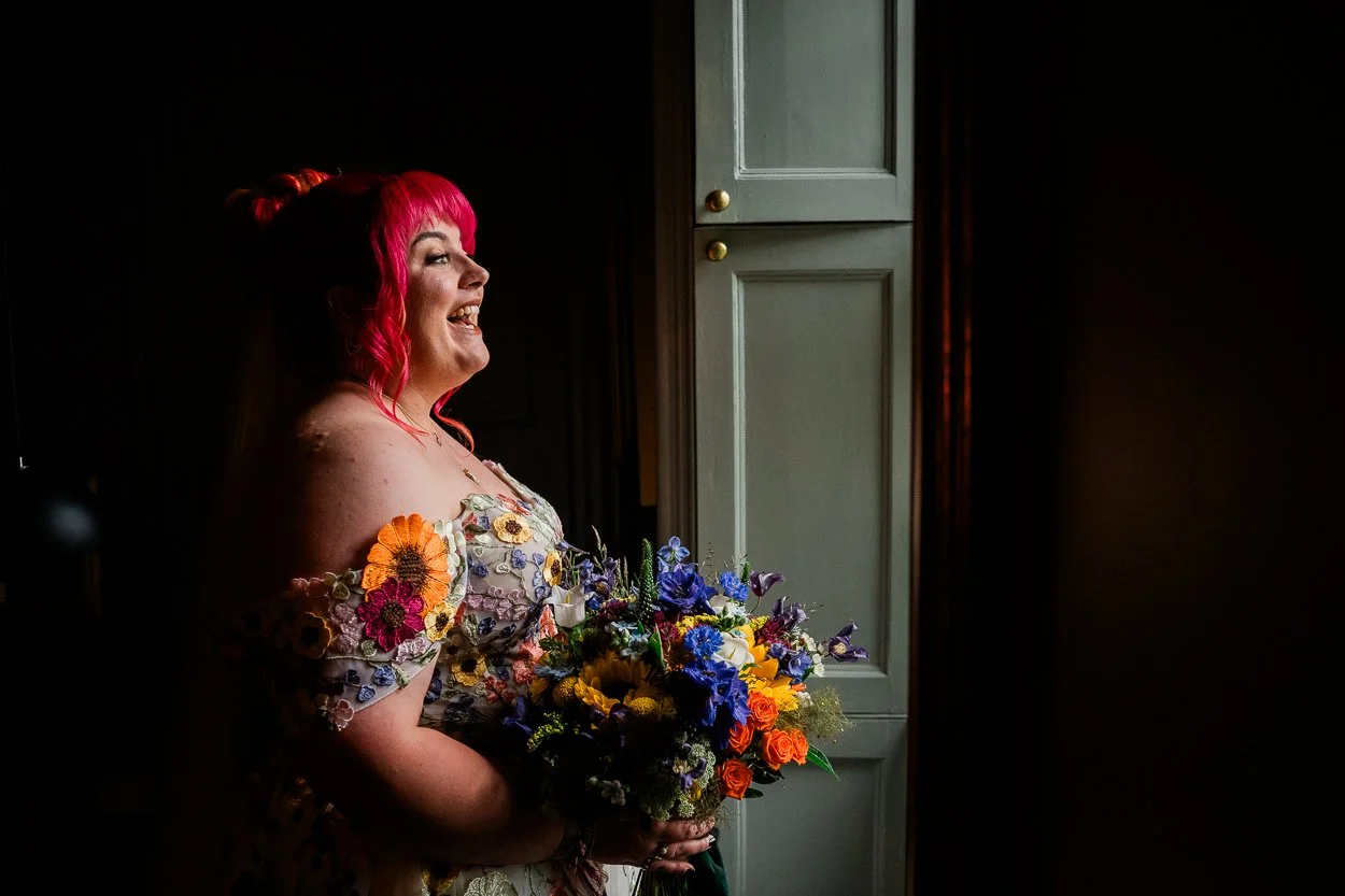 Bride with bright red hair and colourful wedding dress laughing