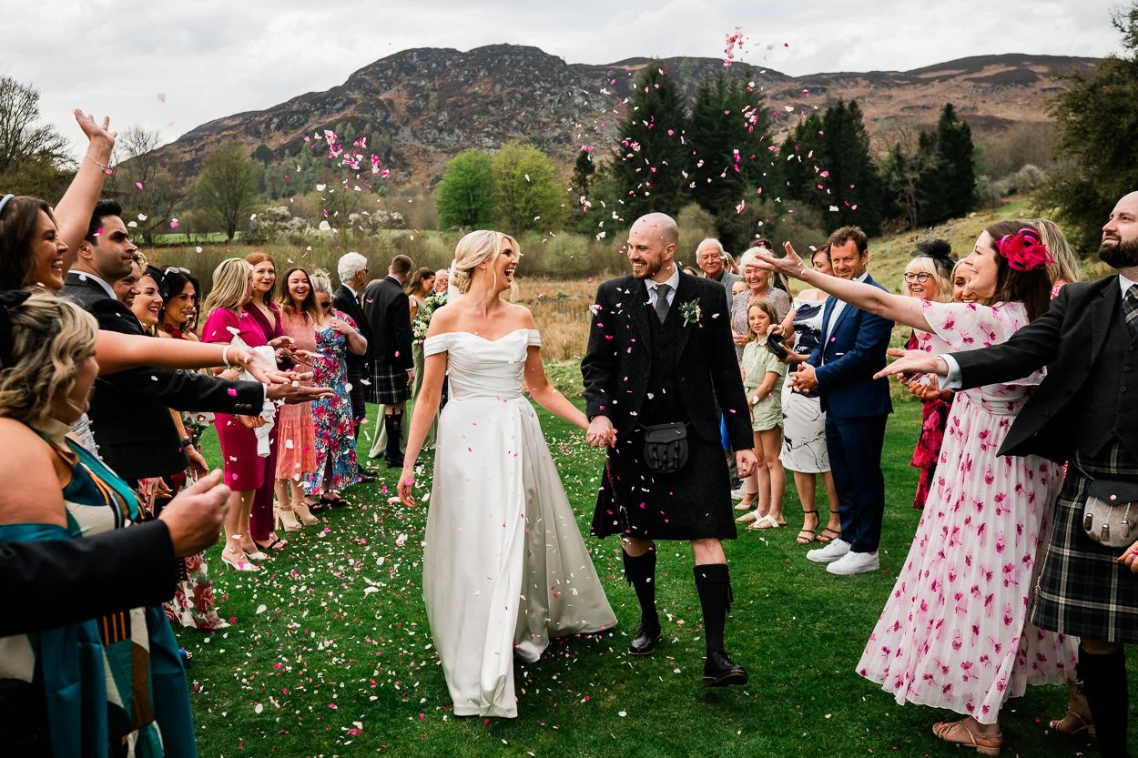 Bride-and-groom-walking-through-confetti-at-cardney-steading