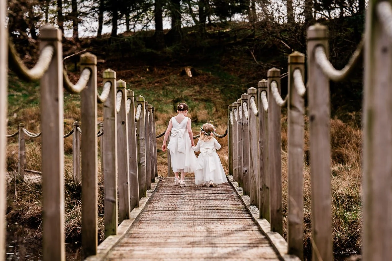 Two-flower-girls-from-behind-walking-across-bridge