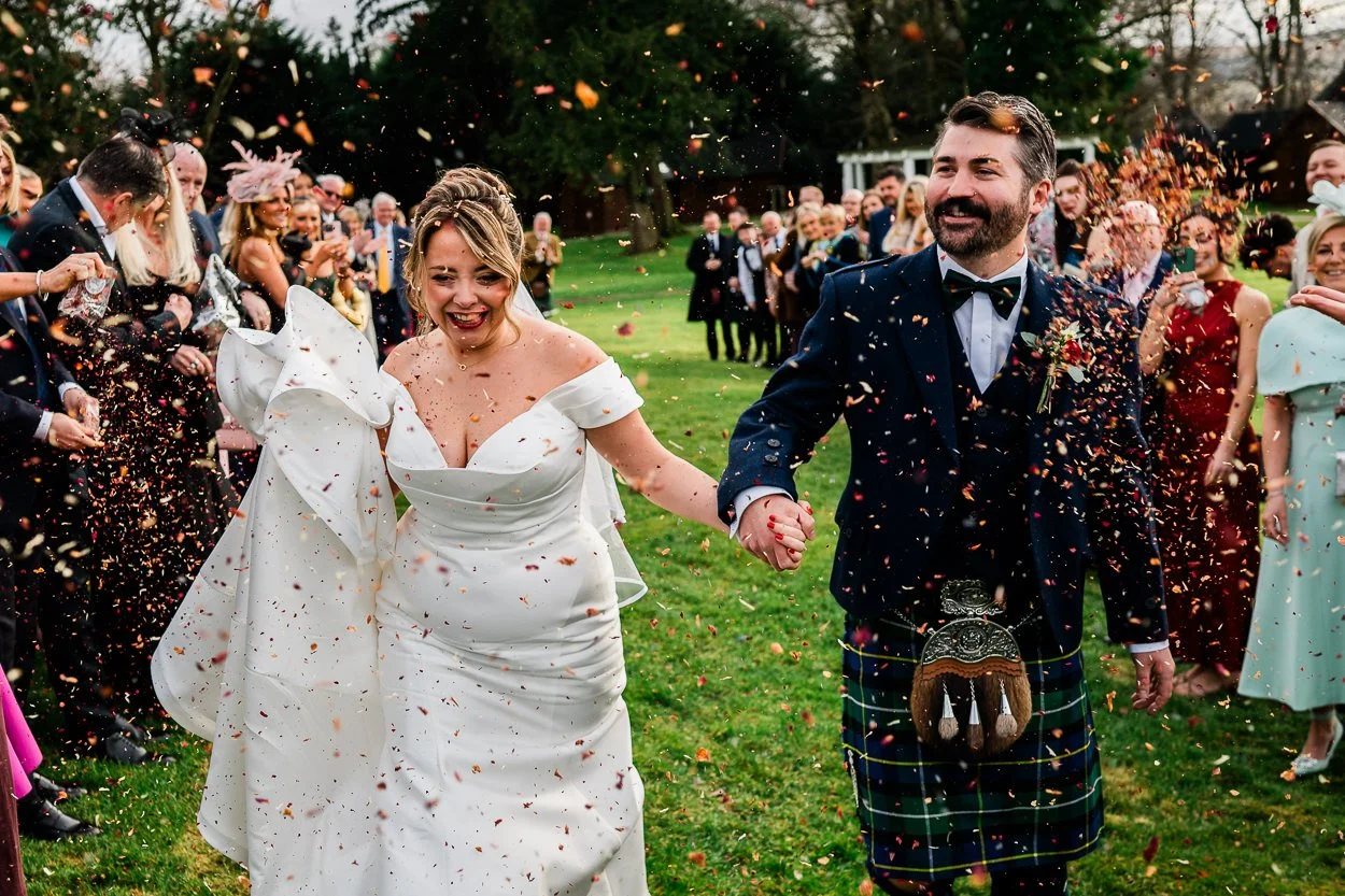 Fun picture of bride and groom walking through confetti