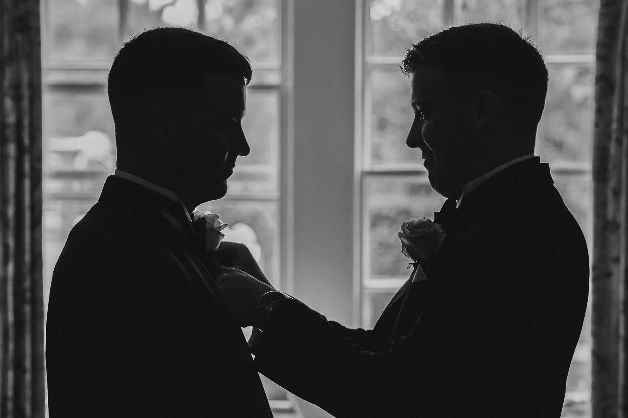silhouette of best man helping groom with tie
