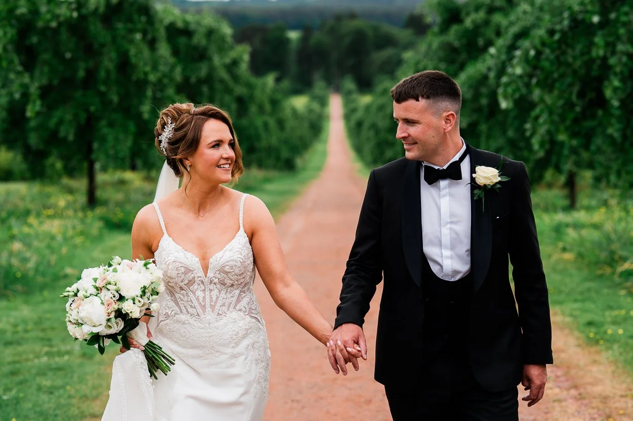 Bride and groom walking down long road at Dumfries House
